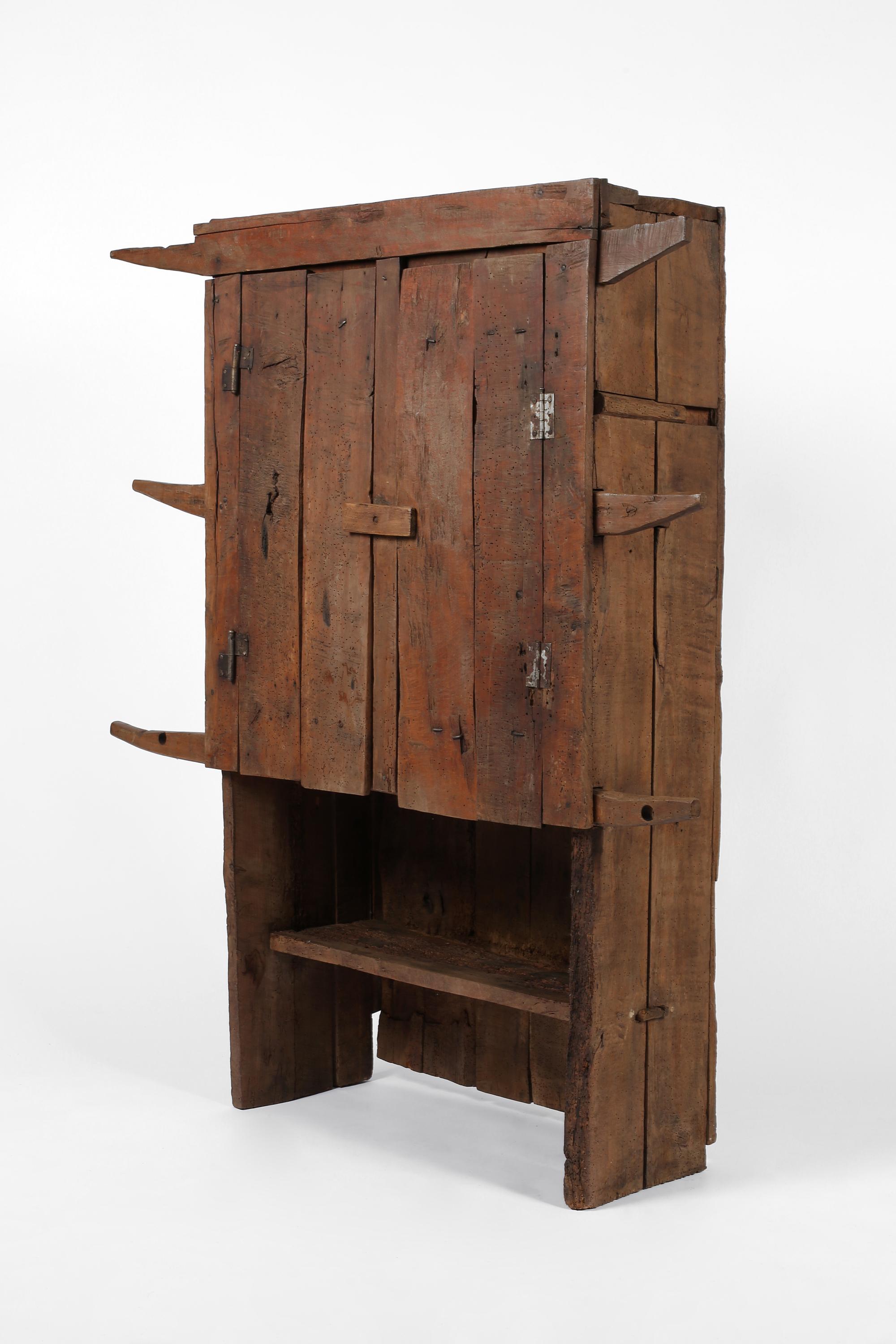 A statement 18th century cupboard from the Carpathian Mountain region. Primitively constructed from roughly hewn mixed hardwood timber, with two planked doors which open to reveal a single shelf within, plus single exterior shelf below. Central