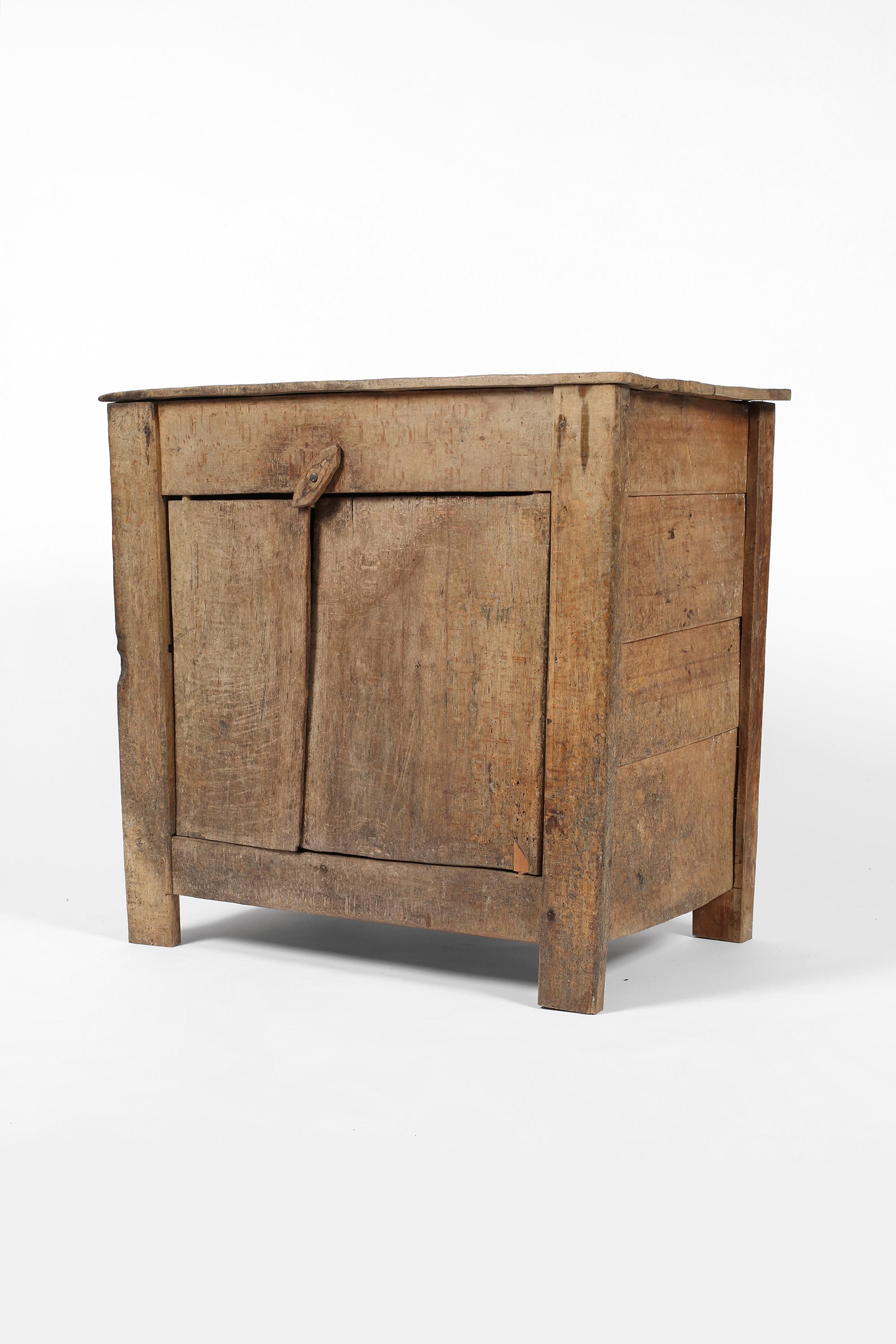 An early 19th century primitive low mountain cupboard in hewn beech, with planked top and two doors which open to reveal a single shelf within. Central European, c. 1800.