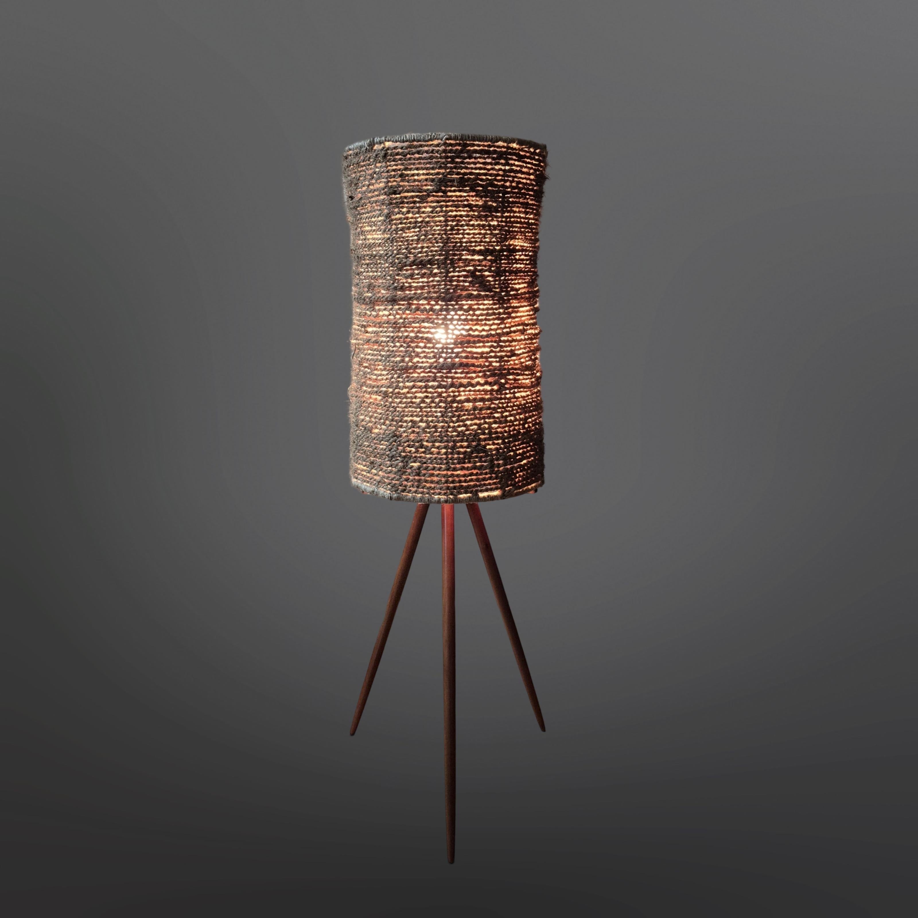 Mid century floor lamp. It has a wooden (teak) tripod base with a cylindrical shade. The shade is hand crafted with natural fiber rope. The upper and lower edge are finished of with natural fiber thread. 

The shade gives a beautiful diffused light