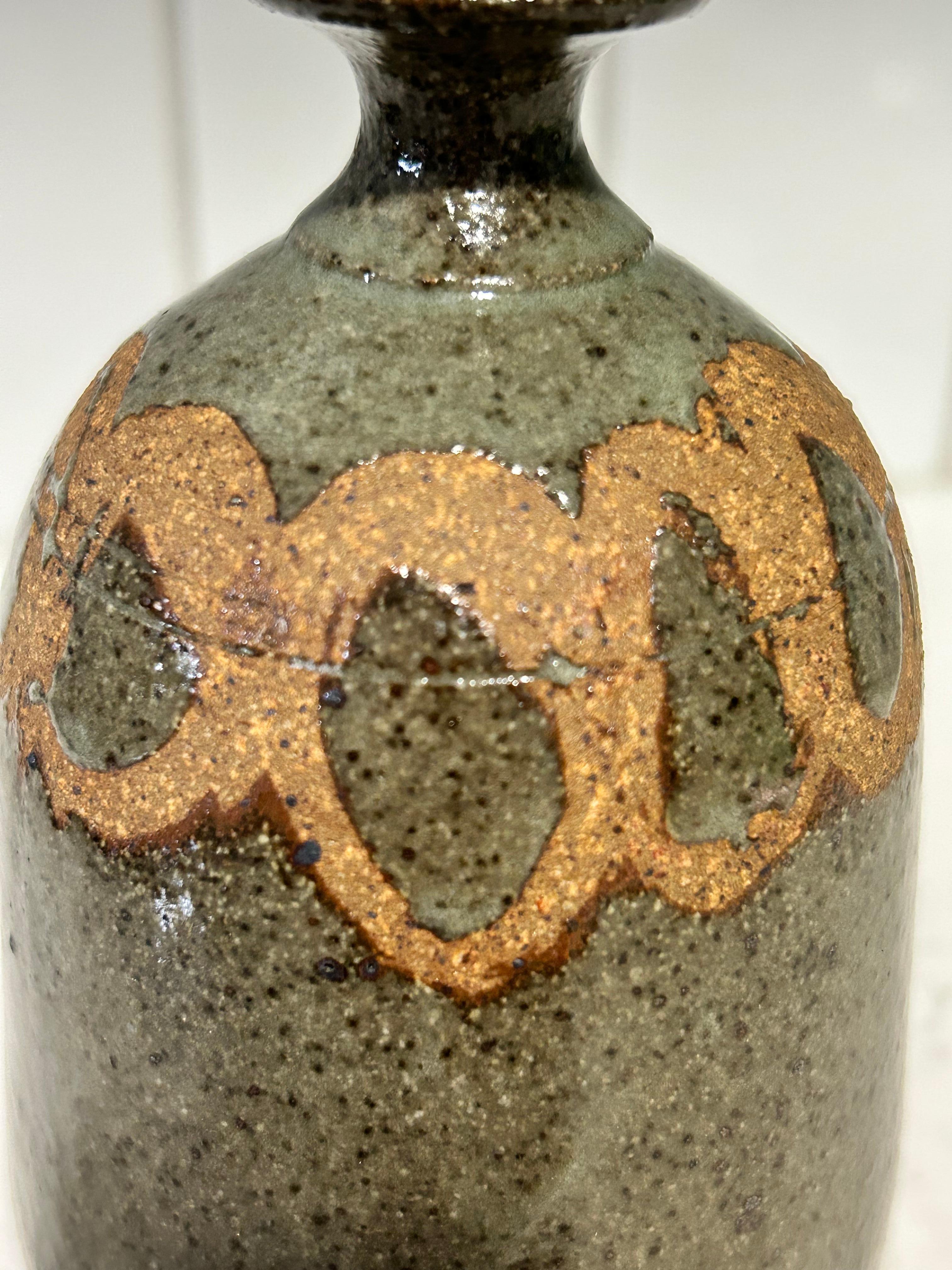 Handgefertigte Vintage-Keramikvase mit rundem Körper und schmalem Hals.  Dieses Stück scheint von der japanischen Wabi-Sabi-Töpferkunst beeinflusst zu sein, die sich durch Einfachheit, Unvollkommenheit und Natürlichkeit auszeichnet.
Der runde Sockel