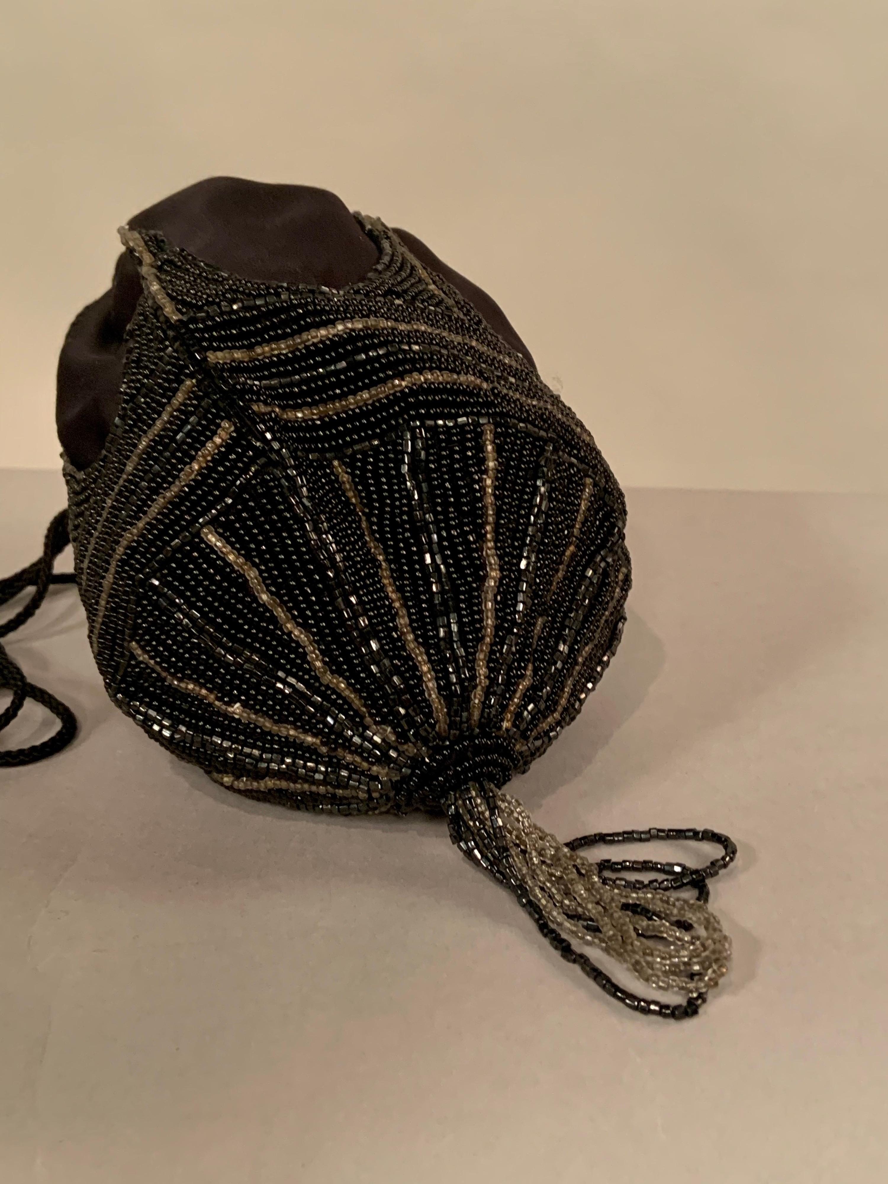 Hand Made in Hong Kong in the 1970's this black satin evening bag has an Art Deco design worked in black and silver caviar beads with a matching beaded tassel.  A woven black cord is used for the drawstring shoulder strap. It is in excellent