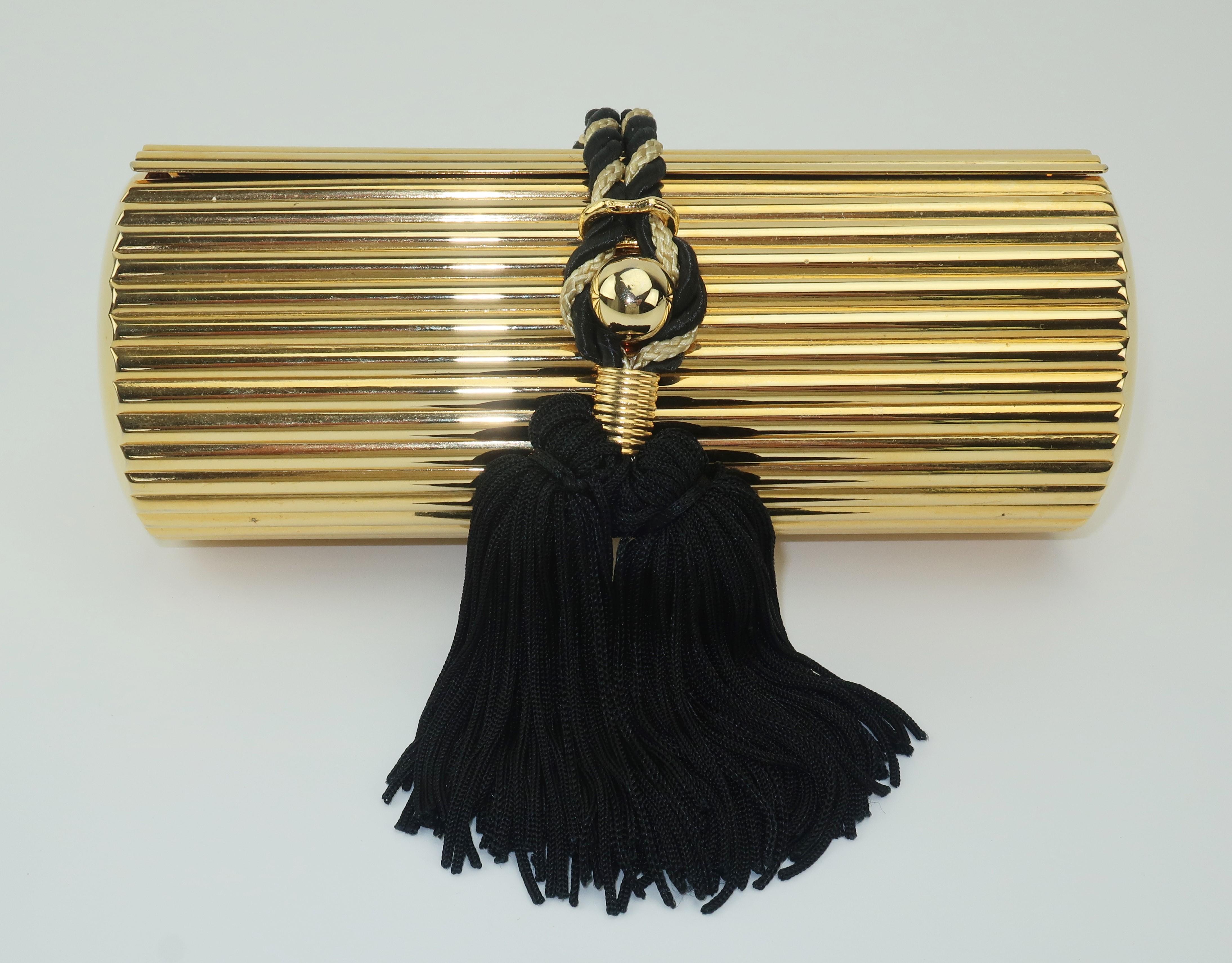 This Walborg handbag is a precious bauble as fun to display as it is to carry.  The gold metal cylinder shape has fluted sides and a nob closure that serves as an anchor for a gold and black braid tassel.  The chain shoulder strap is long enough for