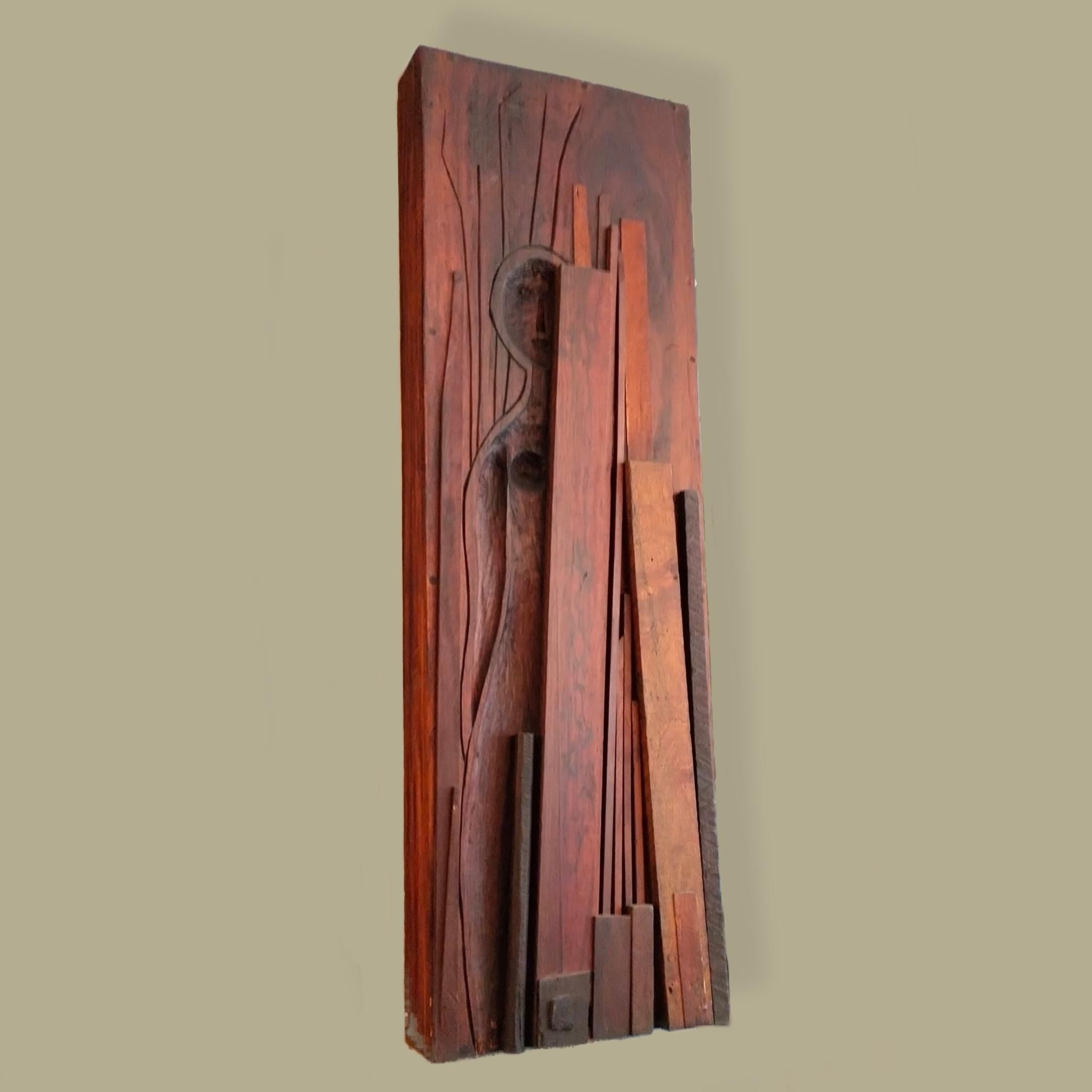 A wood wall sculpture by Swedish-born Mexican artist Waldemar Sjölander. The piece features a woman modeling and looking at the spectator from behind a set of different painter's canvases. The sculpture is made with different pieces of wood that are