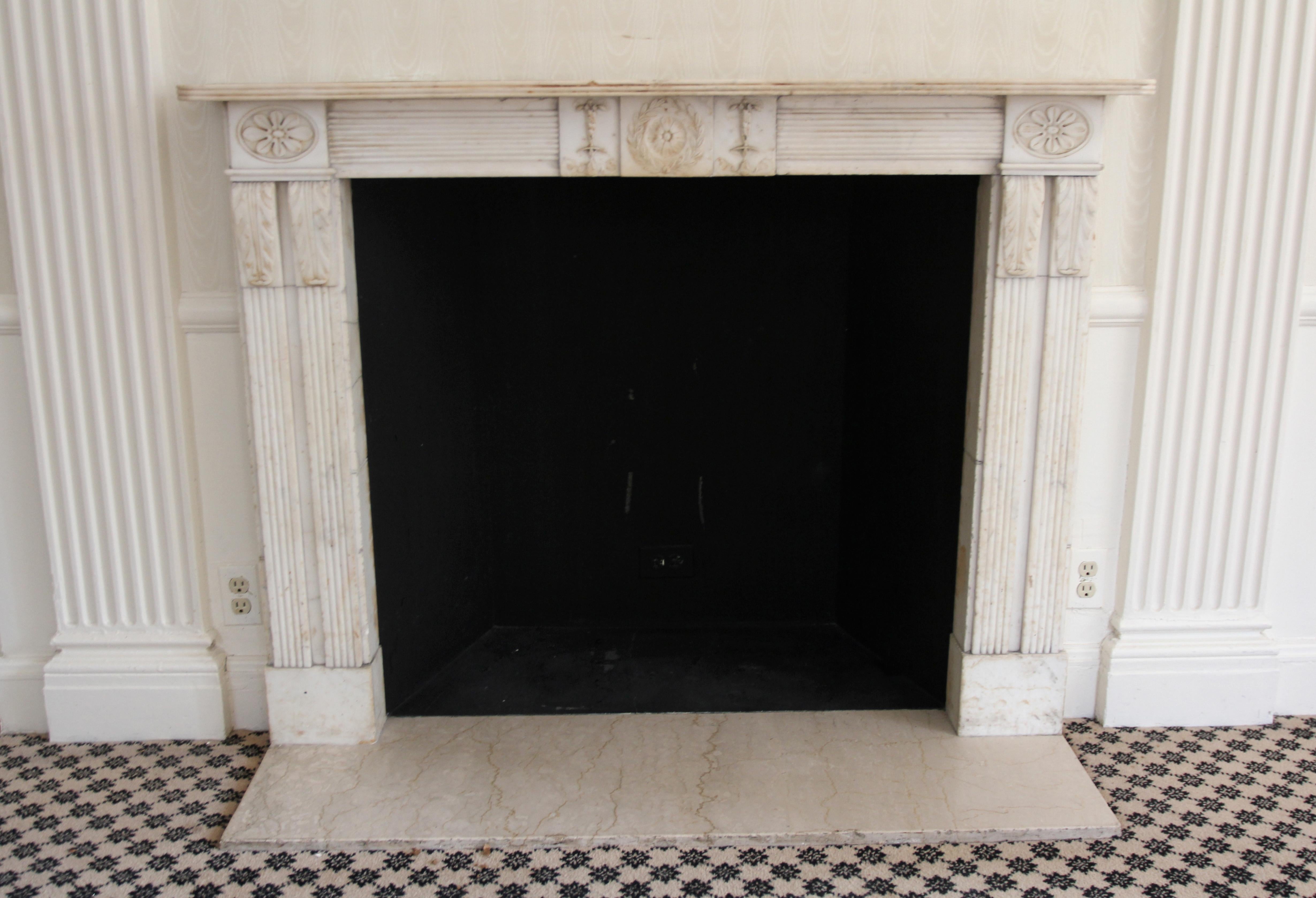 A distinguished English Regency statuary marble mantel from the 1810s, complemented by a newly introduced hearth. The marble maintains its commendable condition, boasting captivating embellishments featuring playful dancing cherubs adorning the