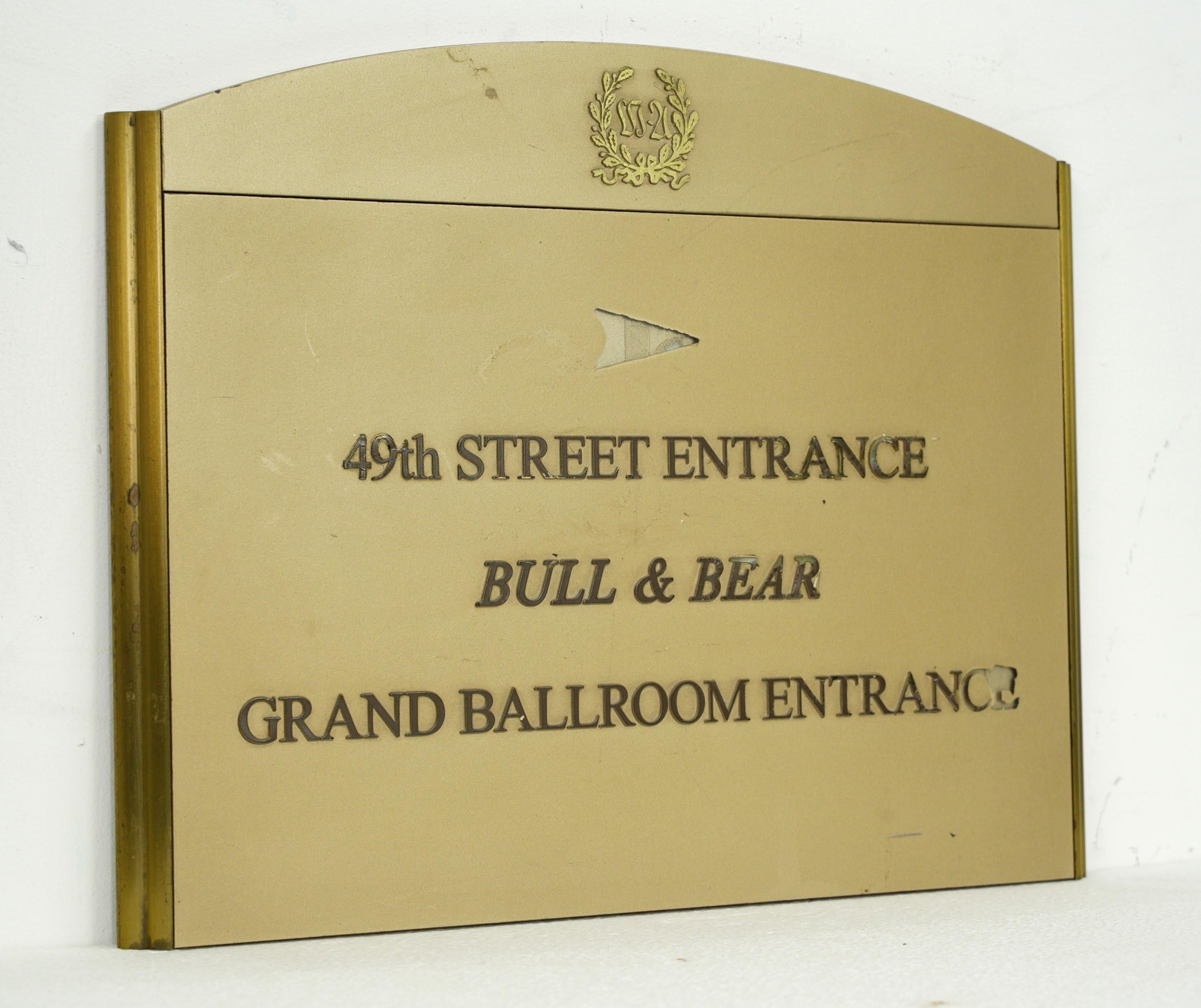 Late 20th Century sign was sourced from the iconic Waldorf Astoria in New York City. Crafted with precision, it features painted directional cues on durable plexiglass framed by a classic brass border and was specifically designed for the Bull &