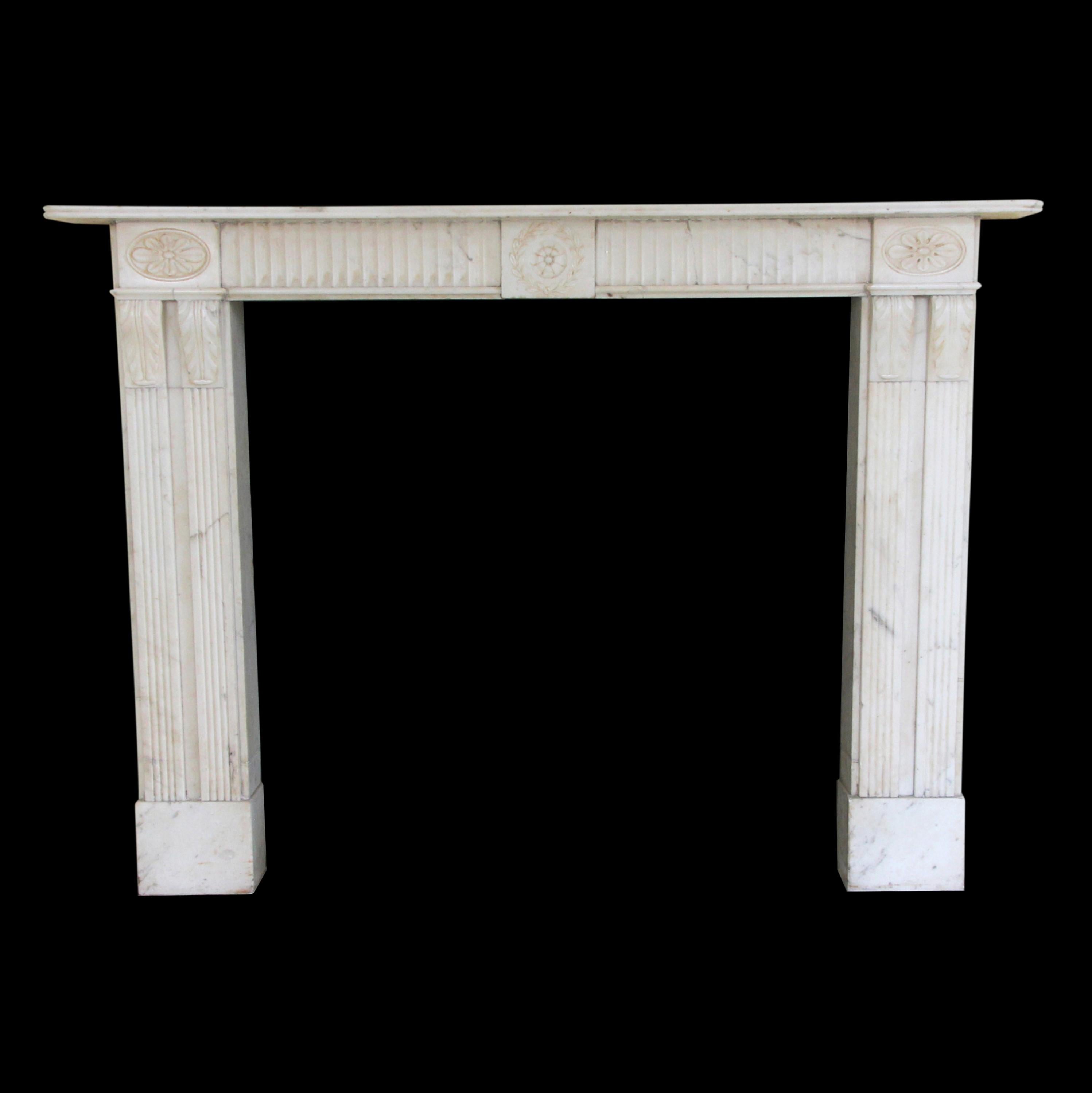 Recovered from the 19th century, this English Regency antique mantel, carved from pristine white marble, offers a glimpse into the past. The vertical supports of this mantel bear the graceful weight of a duo of narrow fluted pilasters adorned with