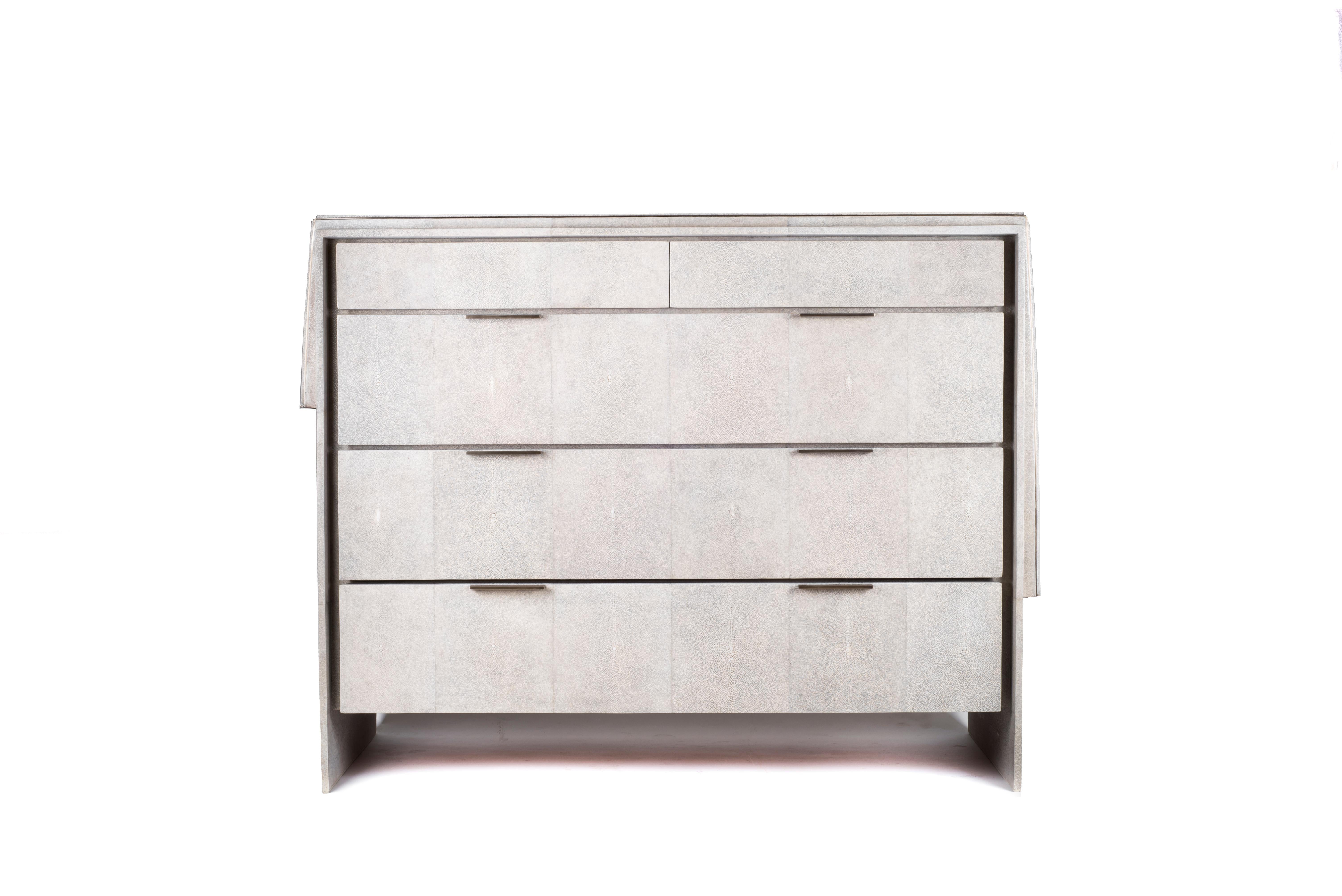 The Waldorf chest of drawers in cream shagreen is a beautifully detailed piece with its asymmetric shagreen overlay on top and discreet metal border indentation. The thin bronze-patina brass handles allow for practically while maintaining the