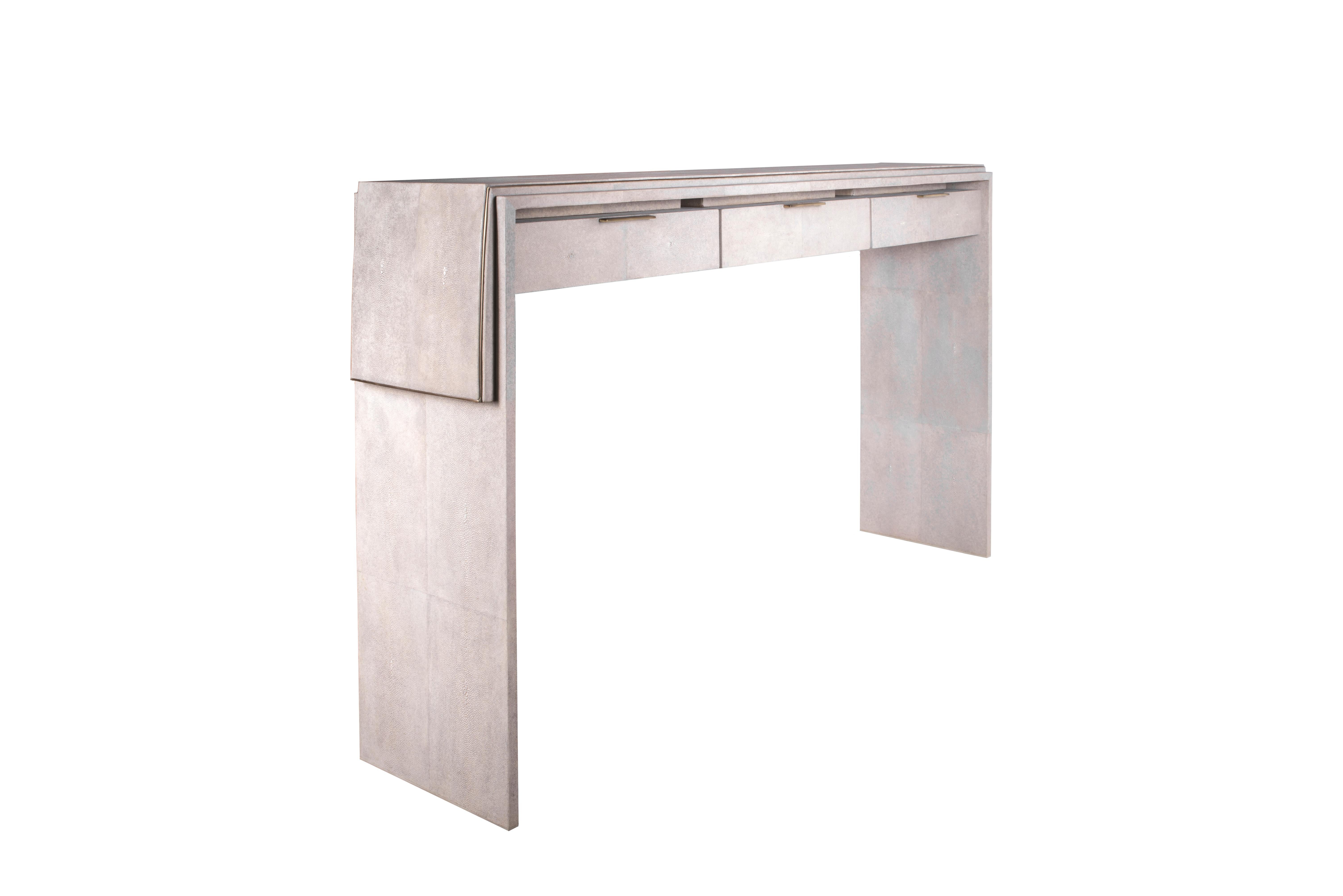 The Waldorf console by R&Y Augousti is an elegant piece with it's asymmetric overlay detail in cream shagreen and the discreet bronze-patina brass metal indentation detailing. This piece includes three drawers that appear as though they are floating