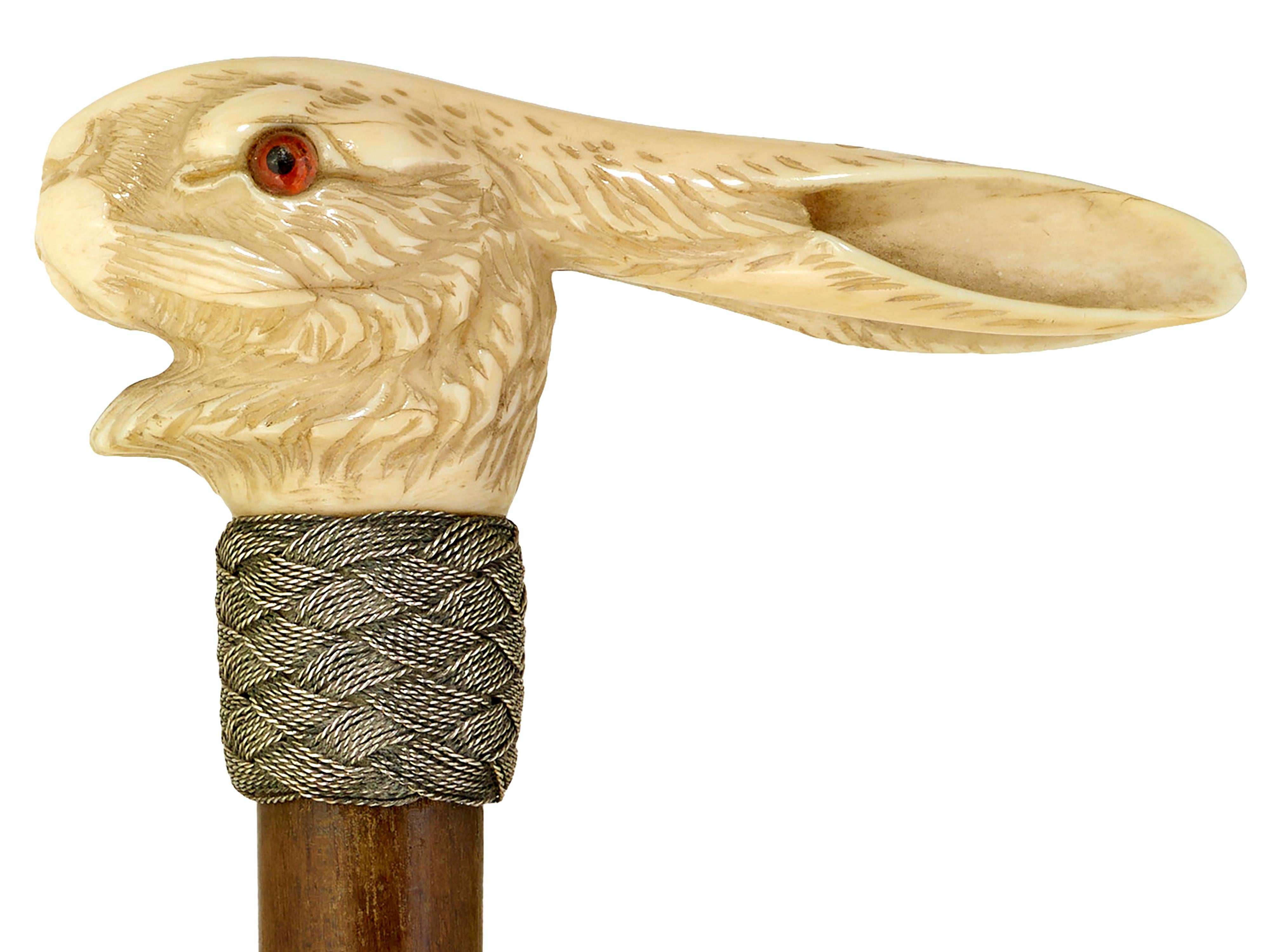 Walking cane with carved hare
Well carved hare with vivid red glass eyes. Plaited silver collar. Snakewood shaft and original ferrule. Excellent condition. 
Will be supplied with Ivory Submission Reference No.