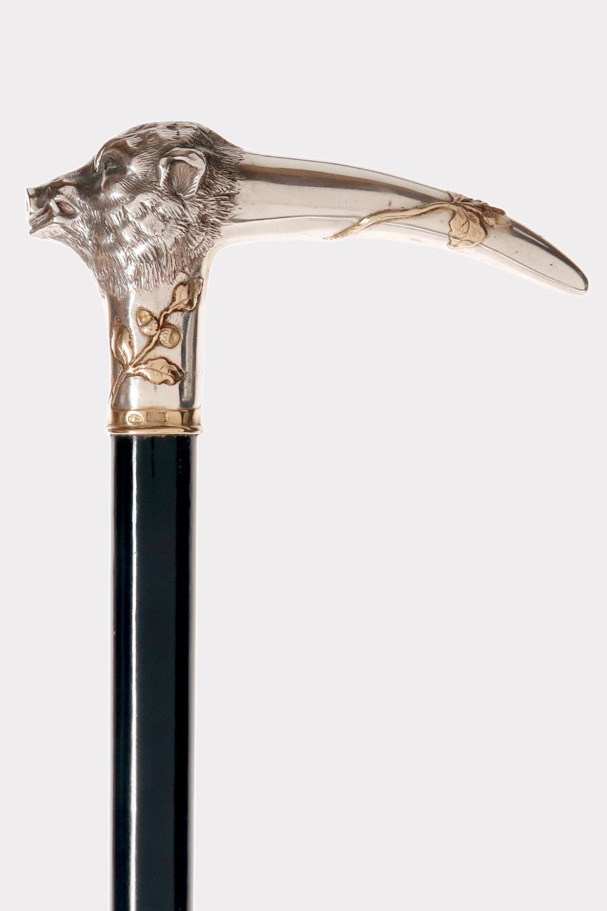 Walking stick: L-shaped silver handle, depicting a boar's head with Baltic amber acorns and embossed and carved leaves. Cabochon garnet stone eyes. Ebony wood shaft. Metal ferrule. Silversmith's marks Josef Ladislav Němec (1871-1943), a goldsmith