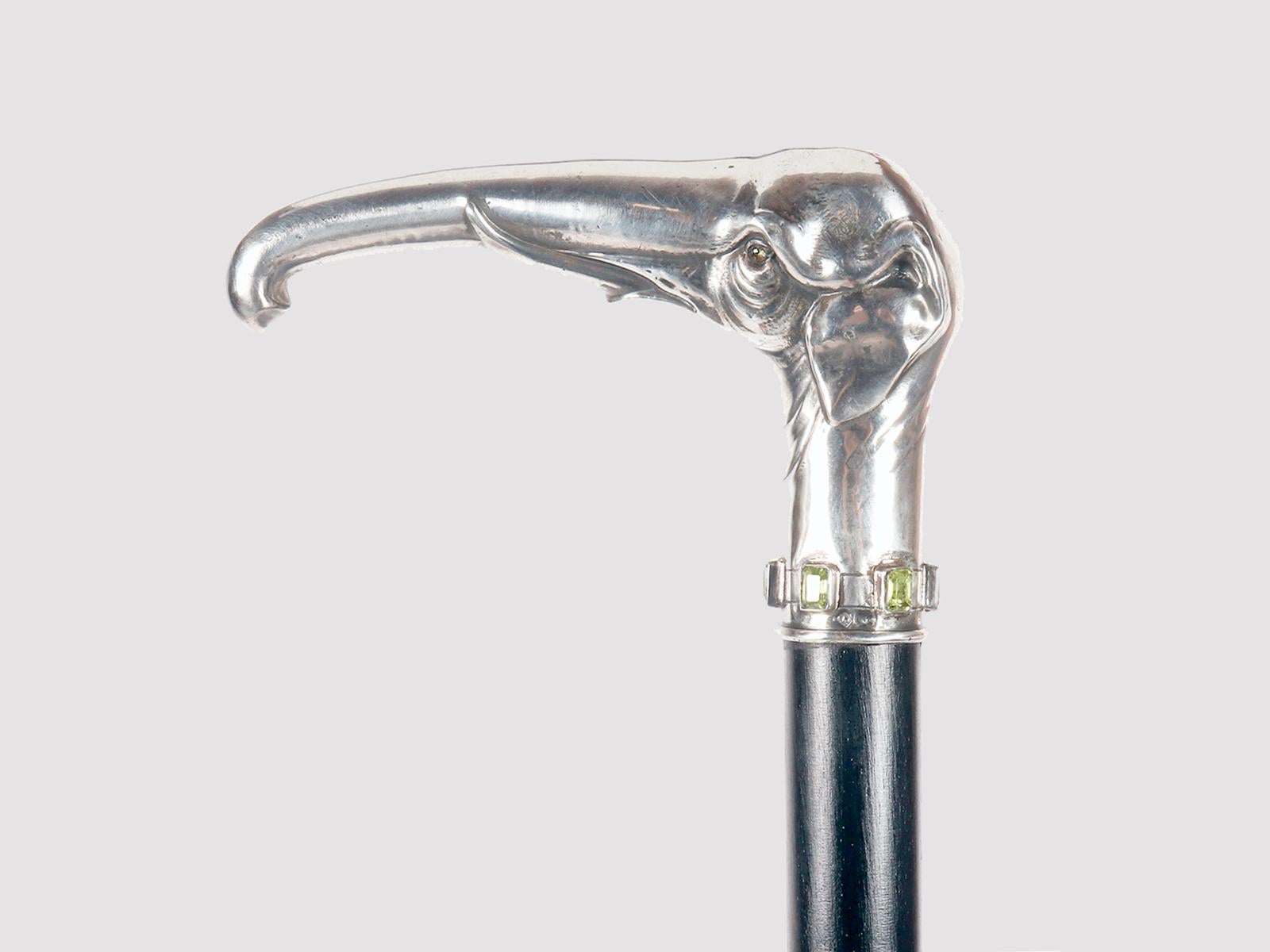 Bastone da passeggio Jewell: manico in argento che raffigura una testa di elefante con proboscide arrotolata in puro stile Art Nouveau. Nel bordo inferiore del barile sono incastonate sei pietre di peridoto taglio smeraldo. Occhi in pietra peridotta