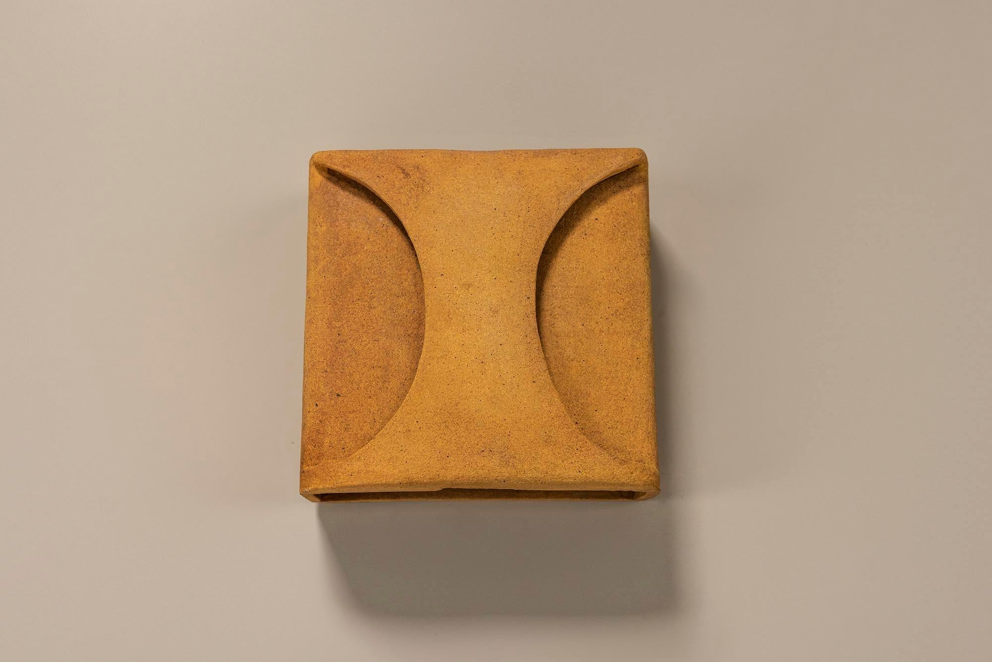 This Guy Bareff wall applique is a stunning fusion of artistry and functionality.

Design‍
Crafted from terracotta and grog clay, this masterpiece boasts a square silhouette adorned with two graceful arches on the façade. These arches not only add a