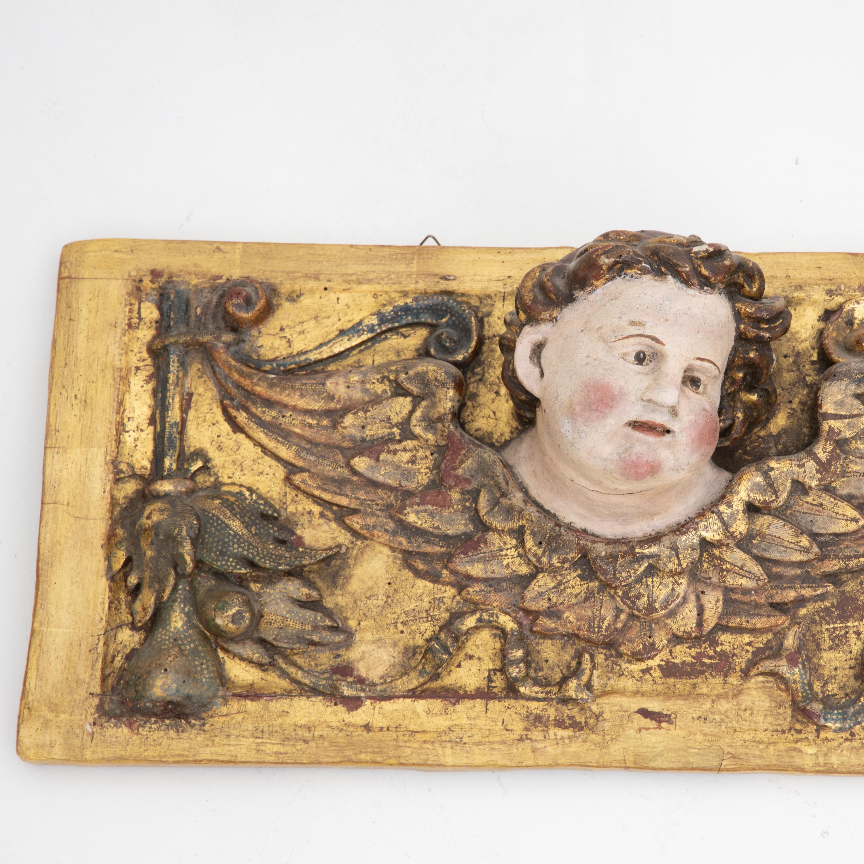 Rectangular wall appliqué with naturalistically painted angel heads with wings. Wood carved and gilded.
