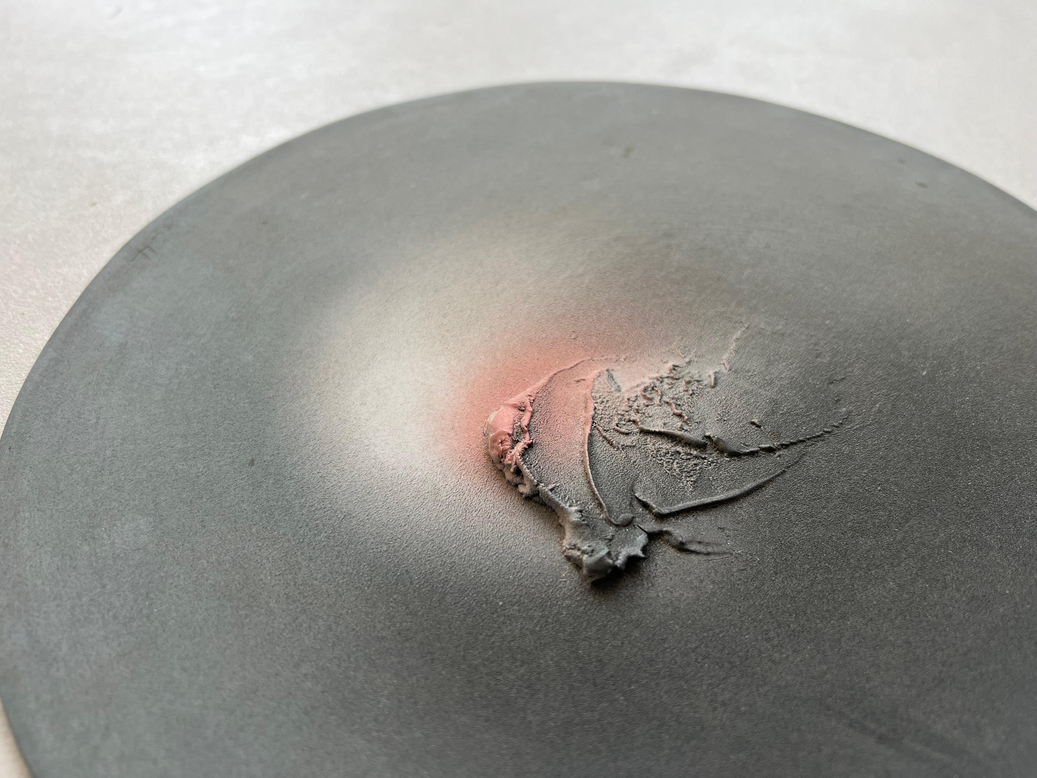 Sculpture in the shape of a perfectly flat disc of opaque gray color with relief elements colored in red, white and brown by oxides and salts. Hand made by Giuseppe Lucietti in 1984

Historical-critical information: The sculpture, called Astrolabe,