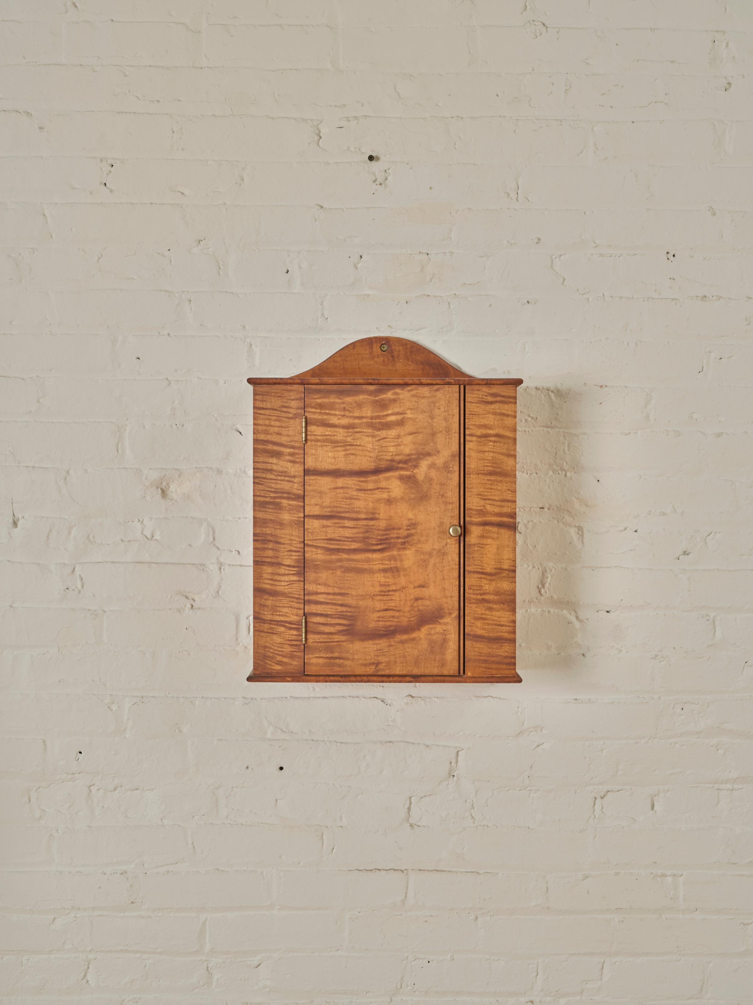 Wall Cabinet by Robert Engvall in tiger maple wood featuring an open interior with two rows of brass hooks.