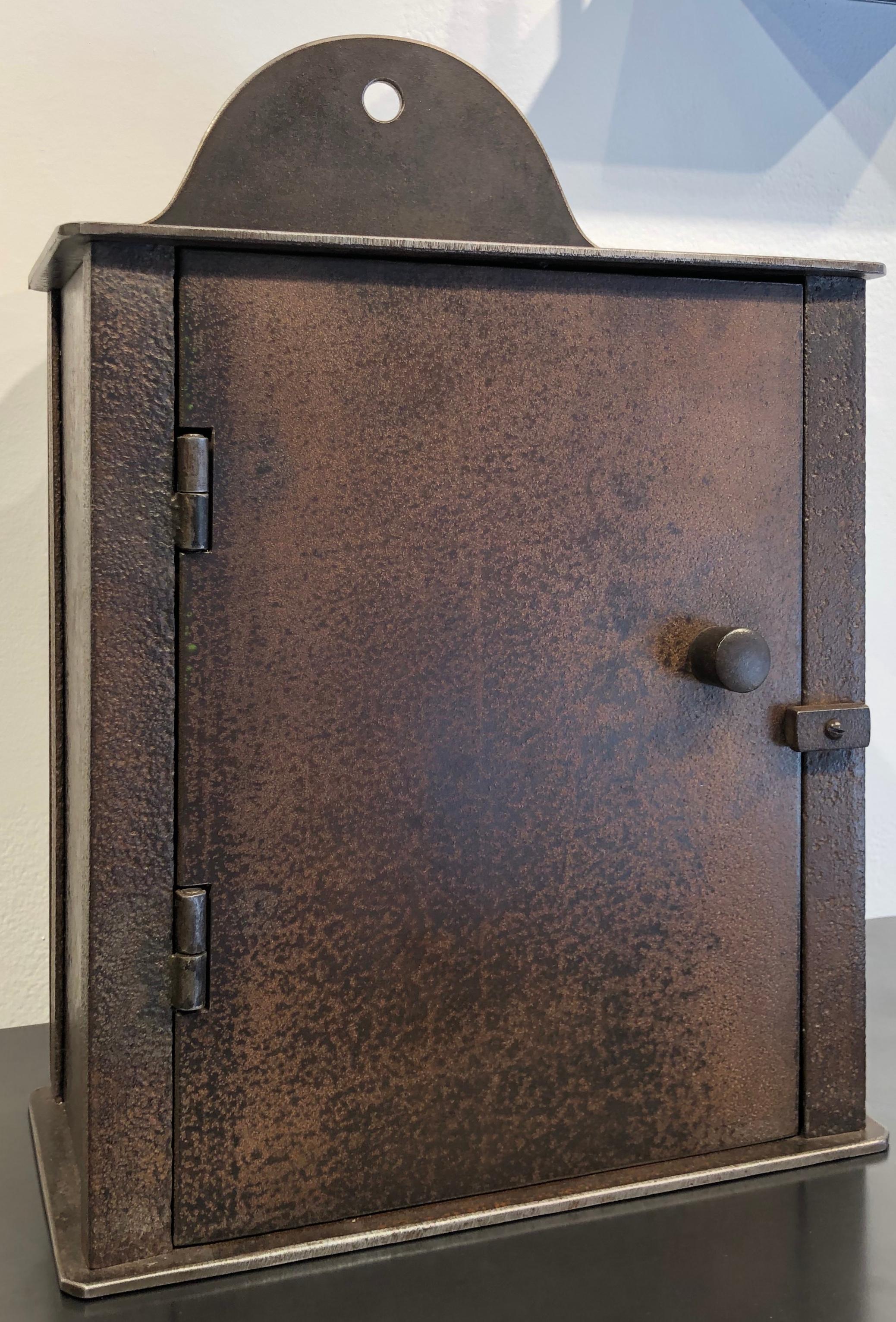 This small wall cabinet is inspired by Shaker furniture. Fully functioning with a hinged door and handmade hardware, this steel cabinet is by renowned furniture maker Jim Rose. With its timeless simplicity, this Shaker piece can stand on its own or