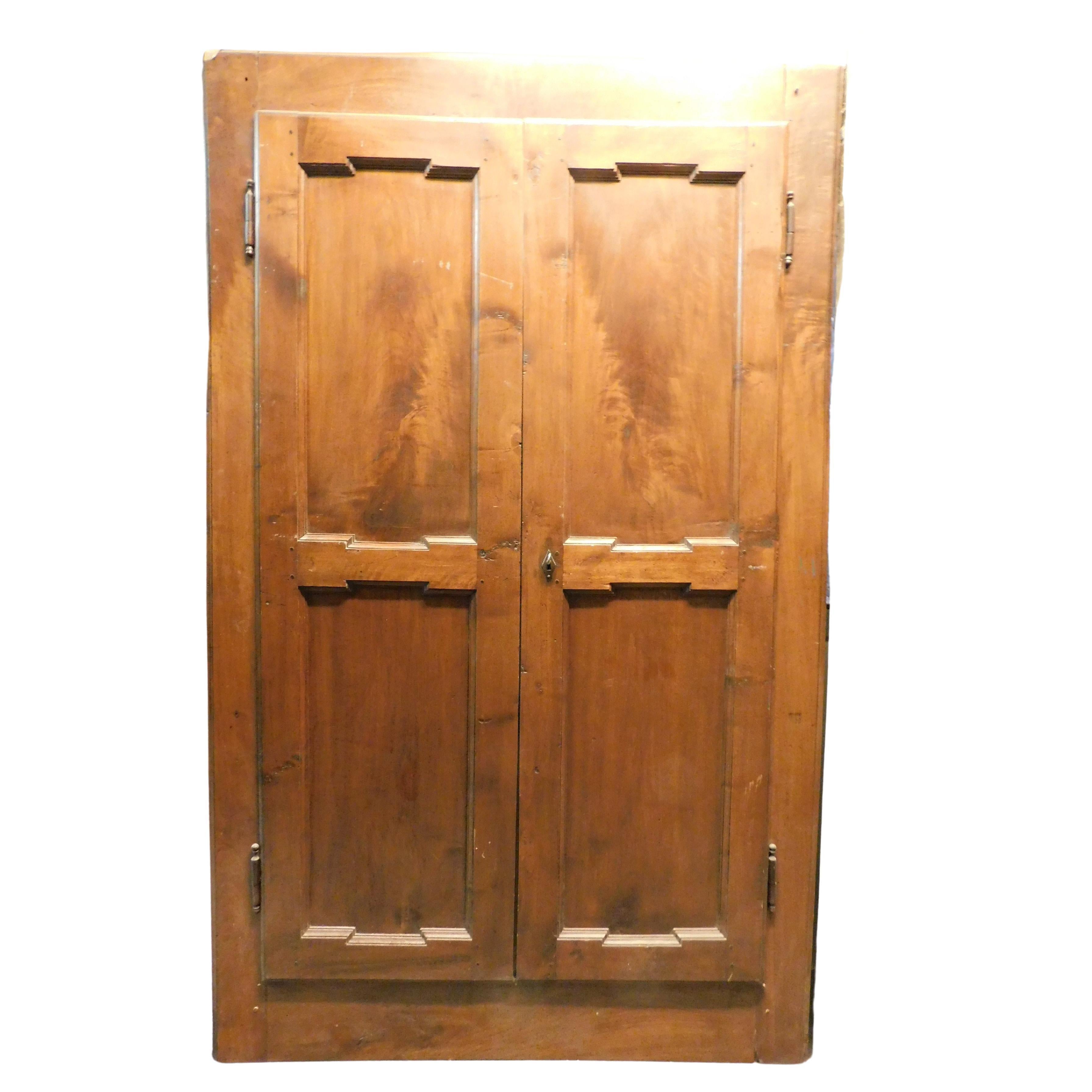 Antique wall cabinet, placard, with two walnut doors, with corrugated panels in the molding, built for a wall wardrobe in a house in Italy, original from the 18th century, it could be transformed into a door by cutting the bar underneath. maximum