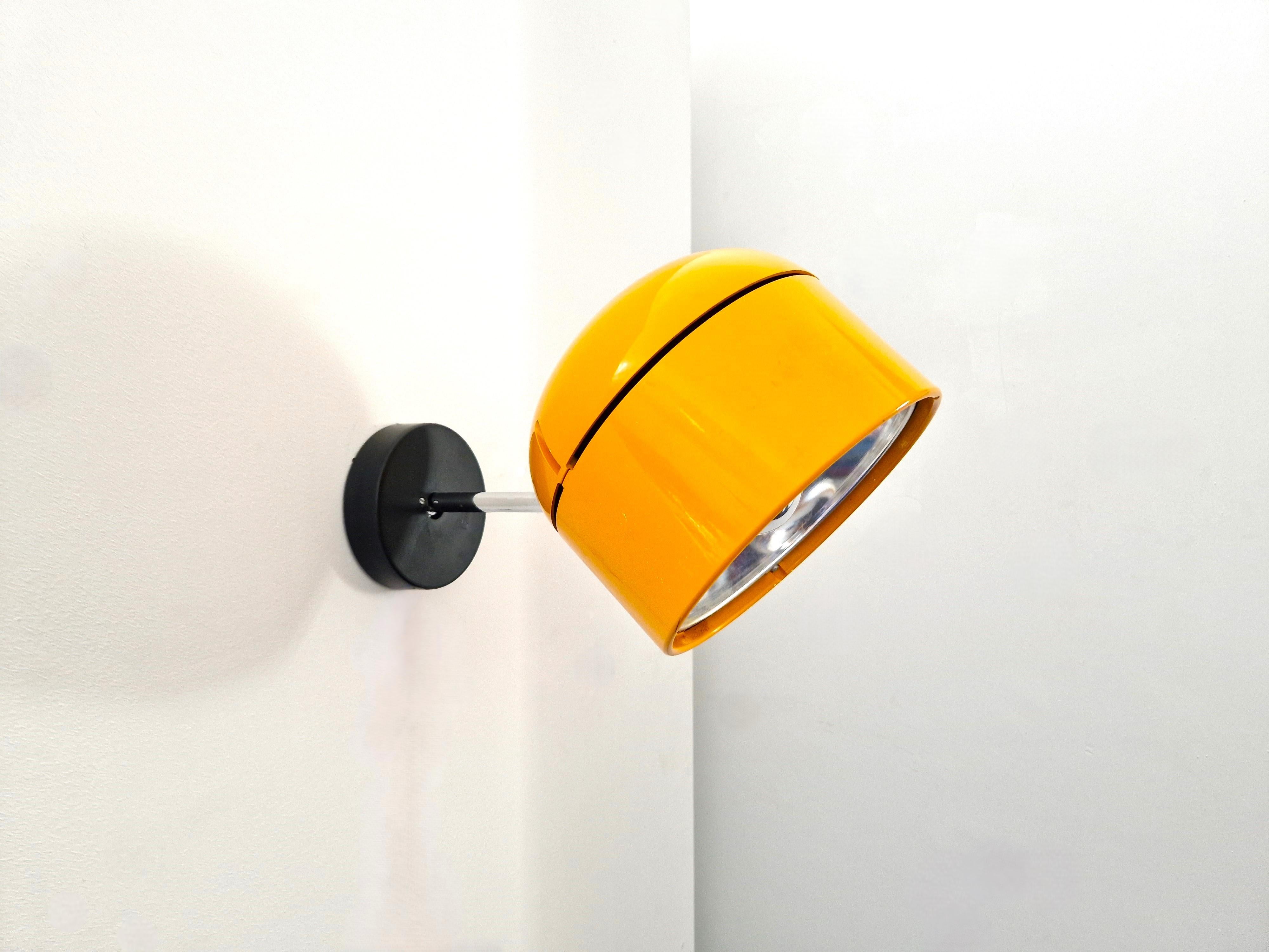 This wall/ceiling spotlight was designed by Arnold Berges for Staff Leuchten in Germany in the 1970's. A stunning design that won the IF Product Design Award in 1973. The lamp has a circular yellow-orange thick acrylic lampshade, perforated with