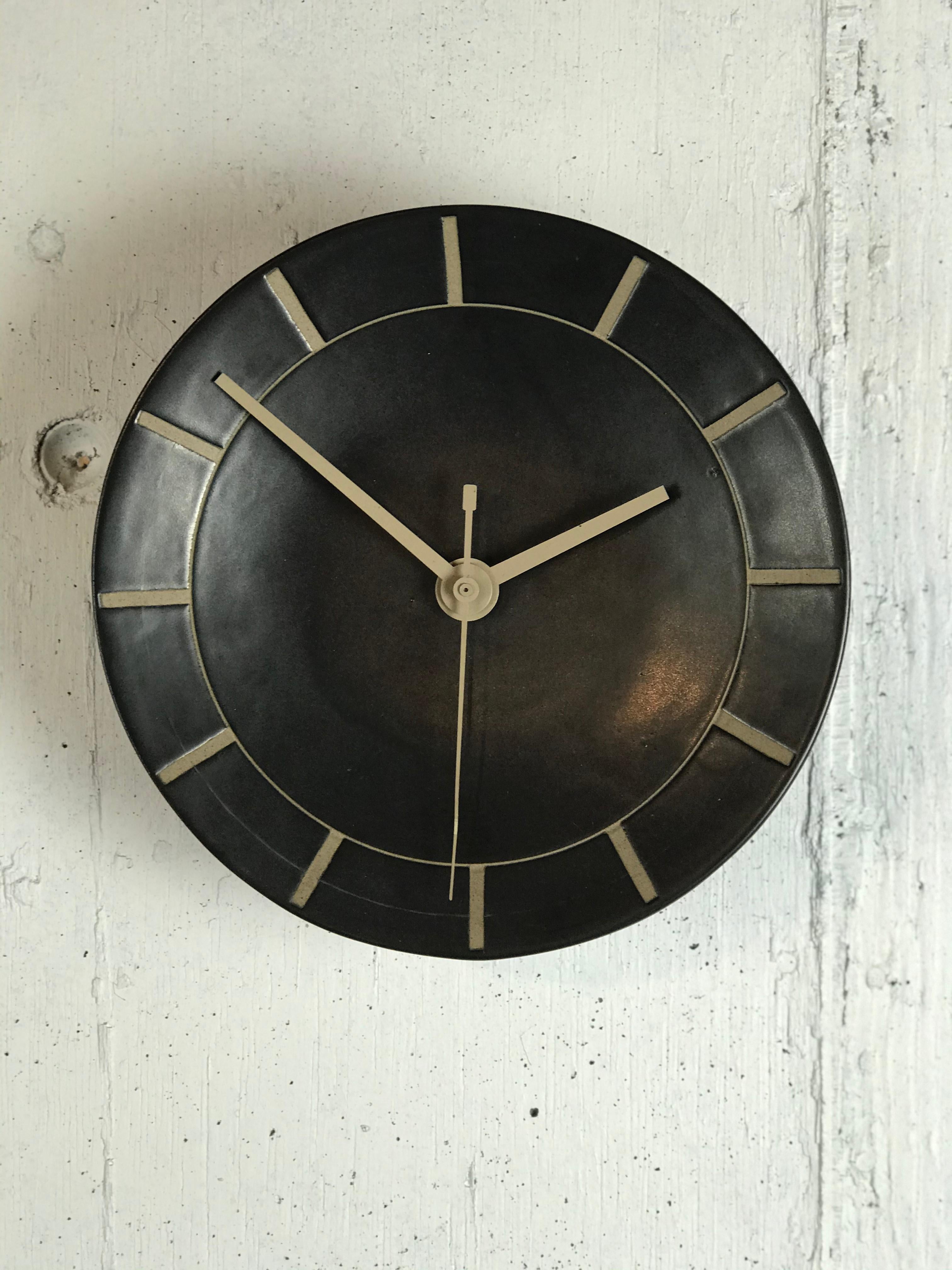 Early and scarce handmade Studio Pottery wall clock in black matte glaze with tan incising, by legendary artists Jane & Gordon Martz. This clock model was the first they produced and first appeared in their 1957 catalog. (See attached catalog photo)