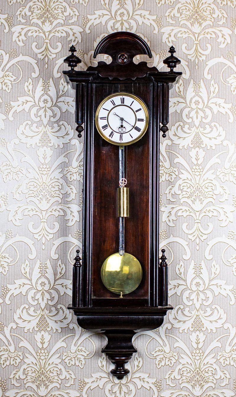 Wall Clock in Black Glazed Wooden Case, 1890s

A wall clock housed in a wooden, glass-fronted case. The case is painted black and remains unrestored. The dial is enameled, and the pendulum lens and the weight are brass. This is a chain-driven clock