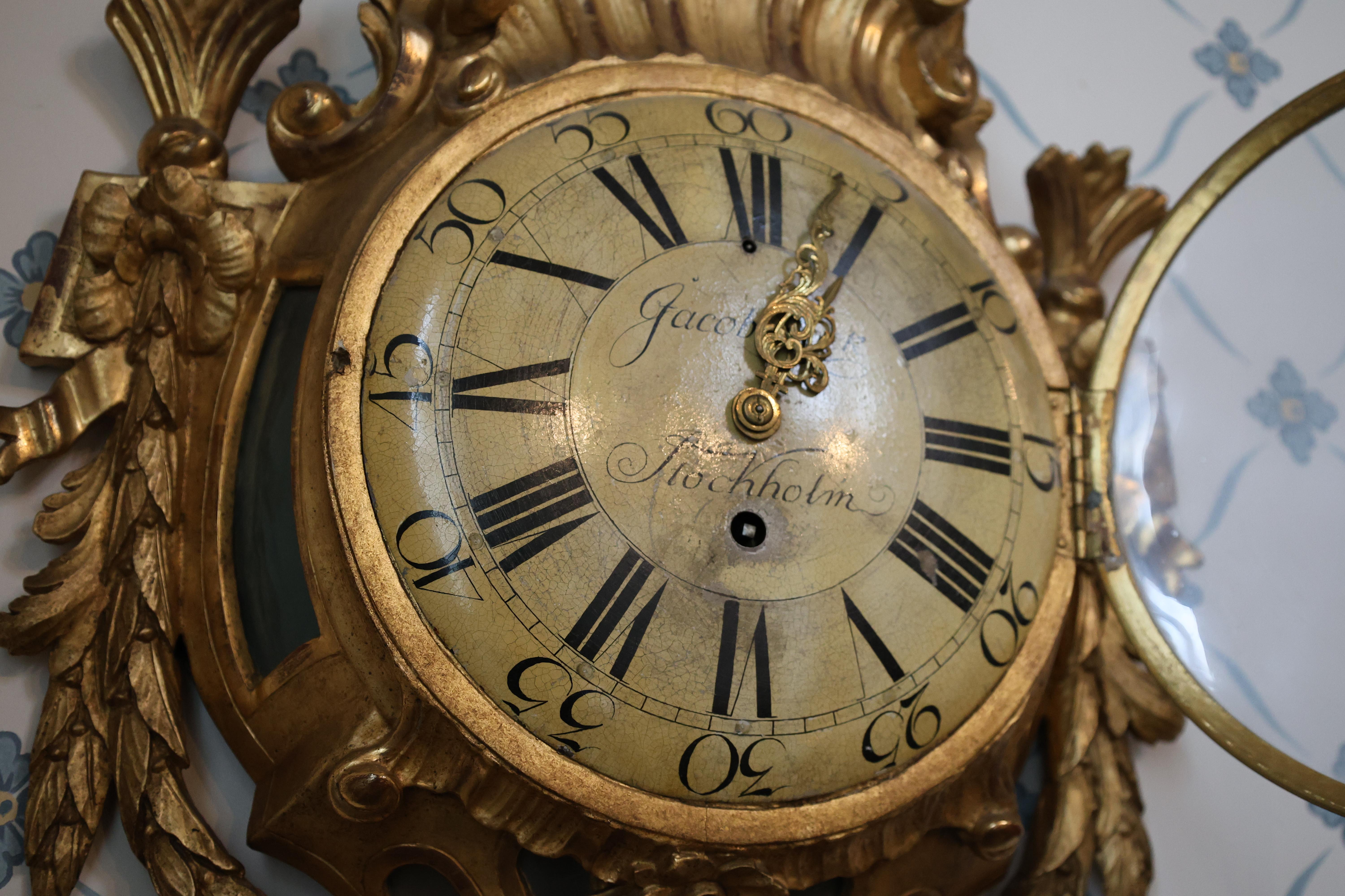A beautifully carved wall clock from the transitional period between Rococo and Gustavian styles. The clockwork was crafted by the renowned clockmaker Jacob Kock, active in Stockholm from 1762 to 1805. The case is entirely carved from wood and