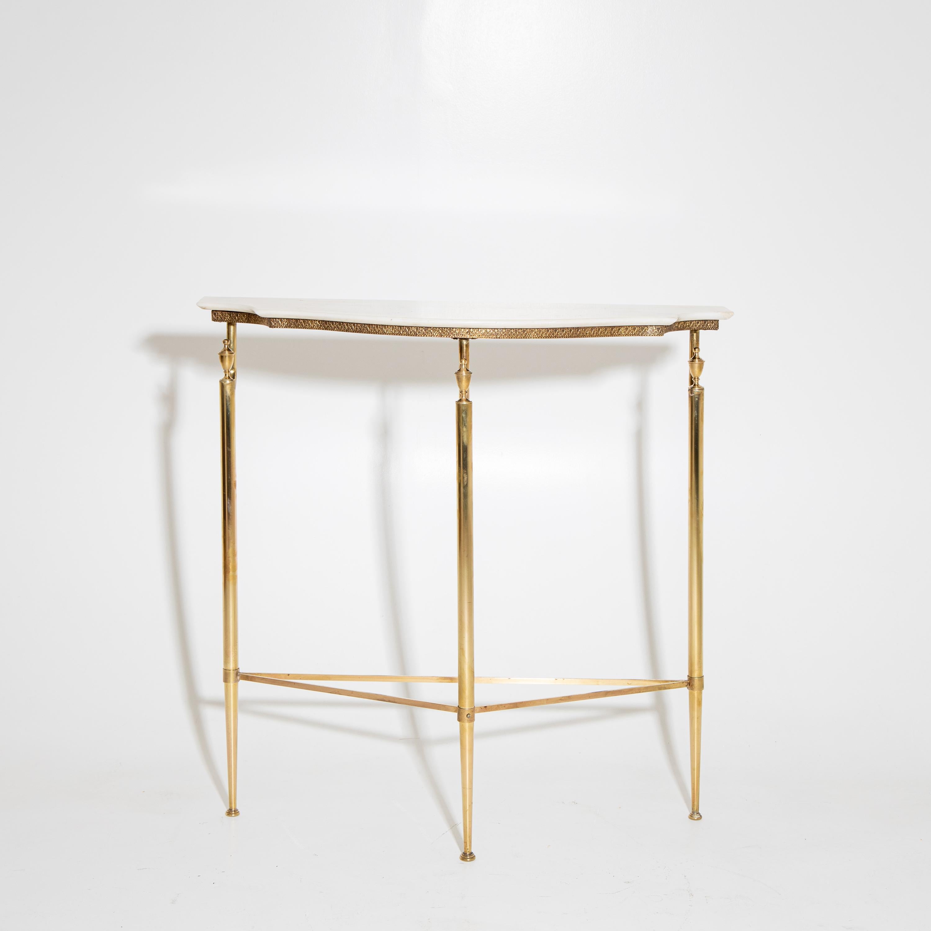 Small wall console with a light-colored stone top on a delicate brass frame with three legs and conical pinnacles.