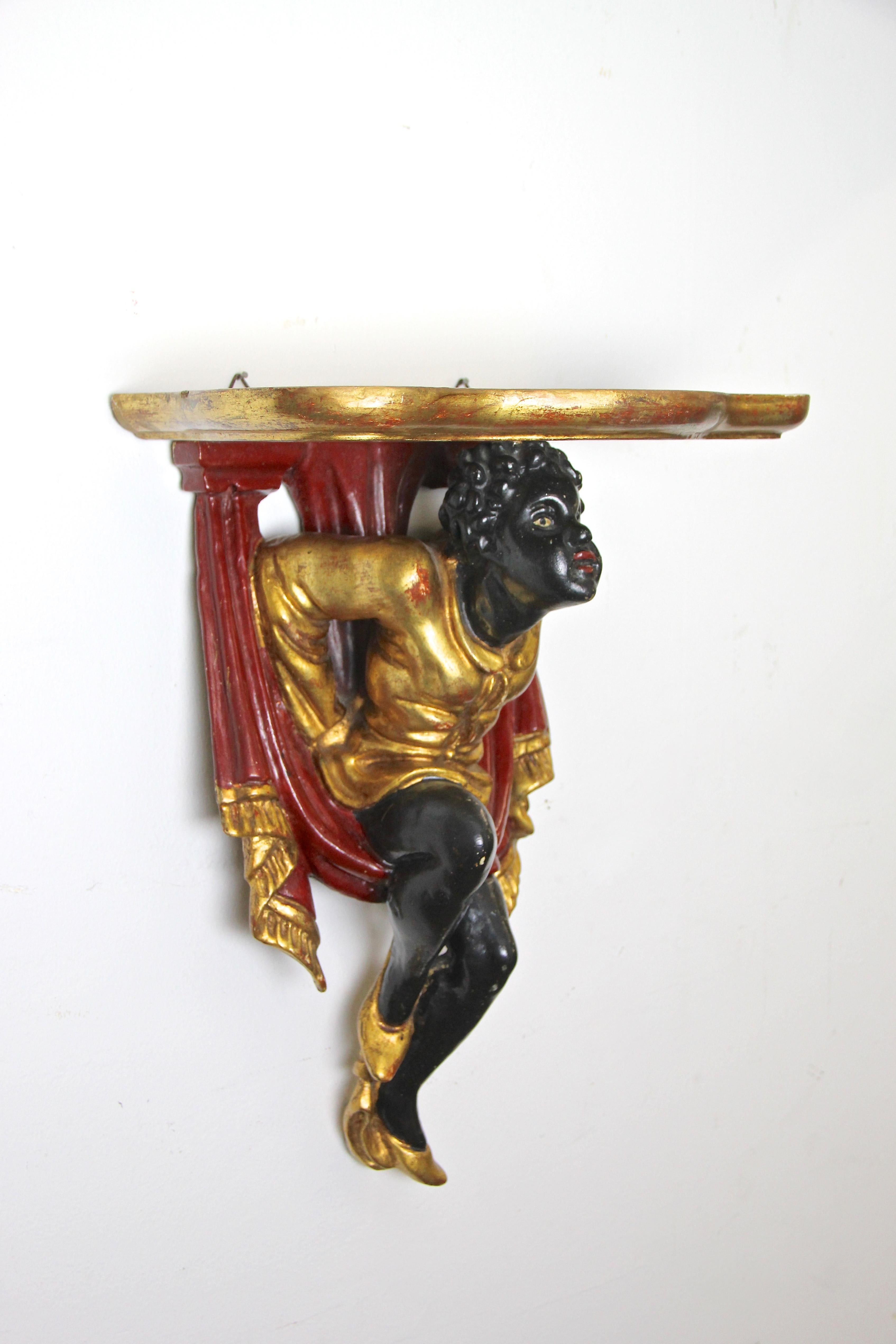 Gorgeous small Baroque Revival wall console from Austria, circa 1910. This beautiful carved wall console depicts a moor in a golden robe swinging in a red curtain. The whole sculpture was hand carved out of one wooden piece, only the gilt top plate