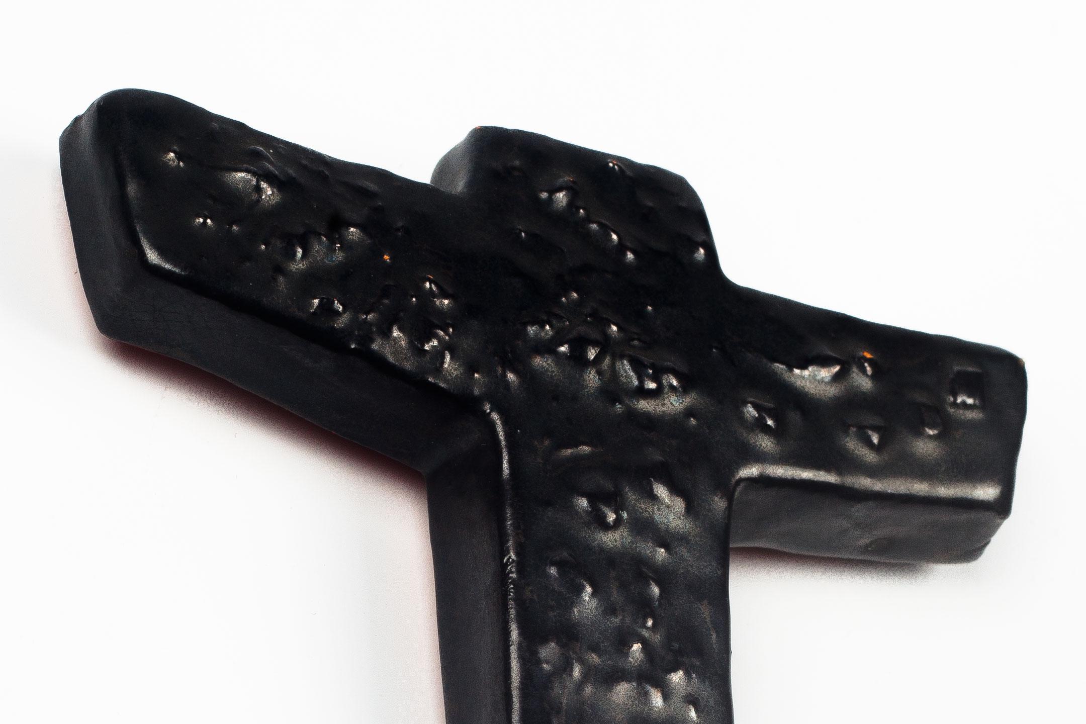 Crucifix in slightly metallic glazed black ceramic with texture. Handmade made in Belgium in the 1970s. 

This piece is part of a large ceramic crucifix collection, all made in Belgium between the 1950 and late 1970s. From modernism to brutalism,