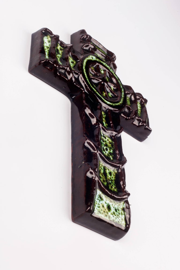 Six inch tall crucifix in ceramic, made in Belgium in the 1970s.
Glossy dark green, brown, black cross with raised spider web and spider at its centre.

This piece is part of a large ceramic crucifix collection, all made in Belgium between the