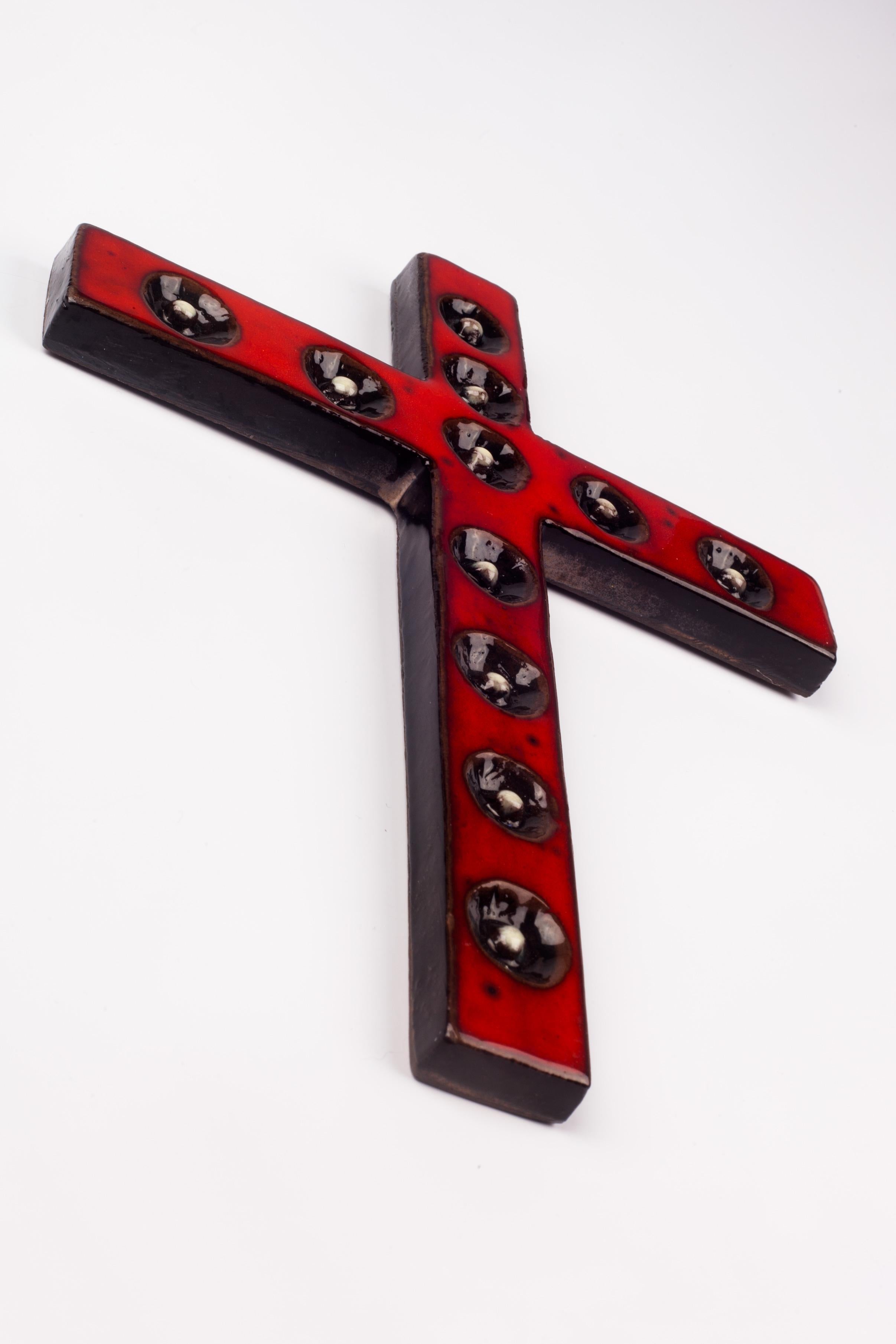 Decorative wall crucifix in ceramic, handmade by an artisan in Belgium in the 1970s. Glossy red cross with concave black decorative circles with white center details in volume.

From modernism to brutalism, the crosses in our collection range from