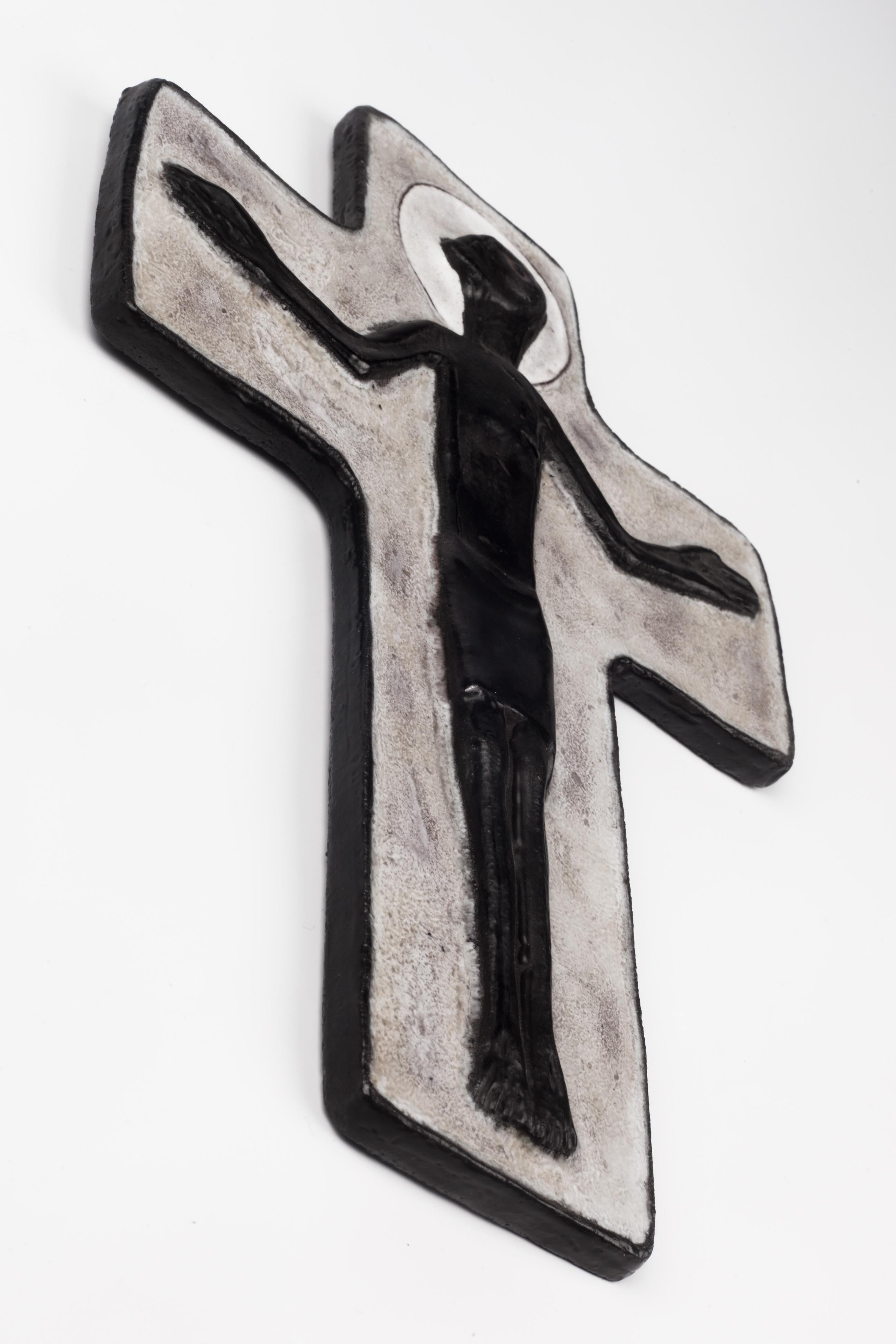 Wall crucifix in ceramic, artisan made by hand in Belgium in the 1950s. Glossy dark grey, nearly black Christ on glossy textured matte grey cross. Brutalist almost Primitive volume and lines showing deep presence. Raw and delicate. 

From