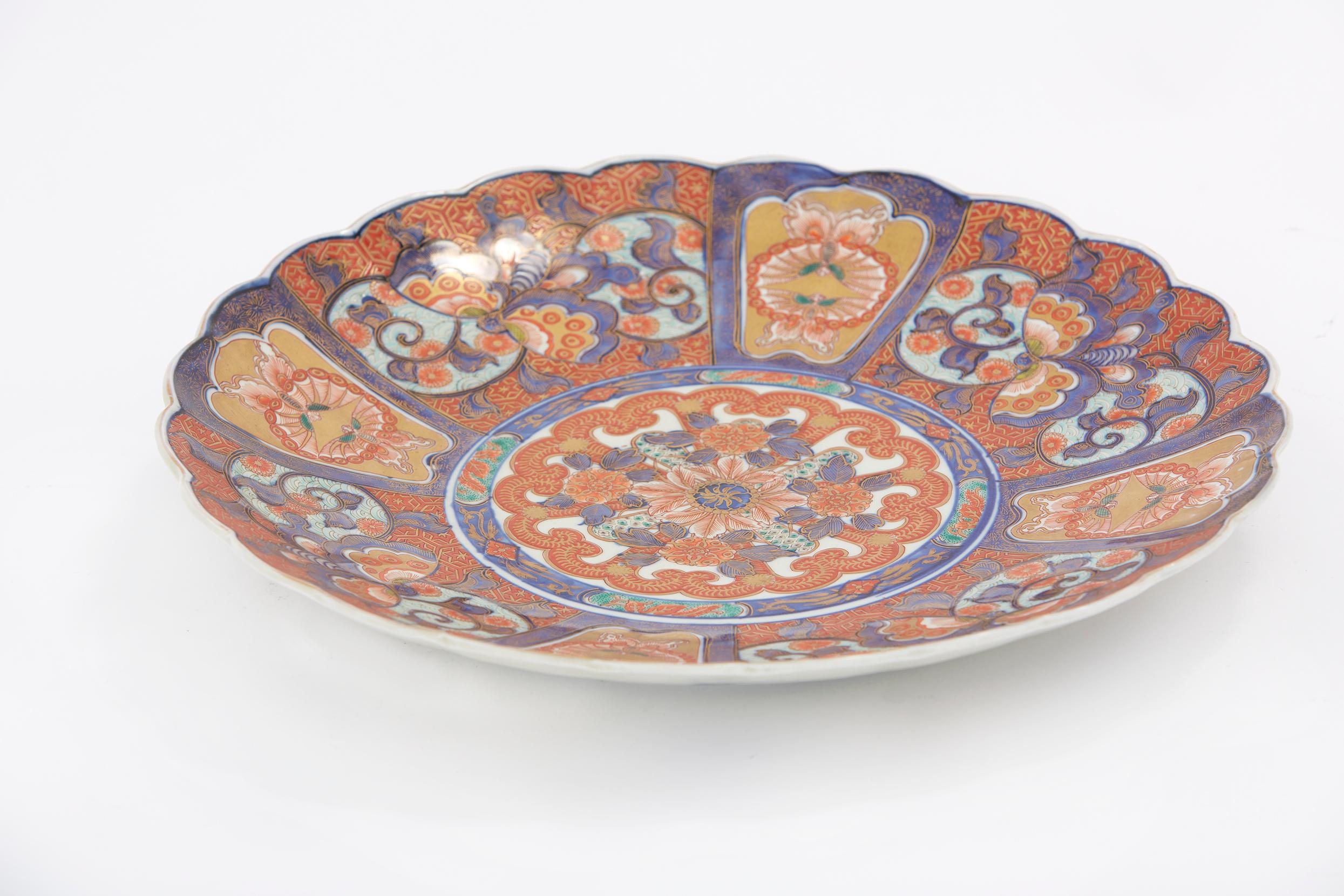 Large hanging wall decoration / centerpiece, Imari porcelain import charger. The Asian ceramic platter features hand painted floral decor with gold gilt accents. The charger is in excellent condition and it is highly embellished with finely