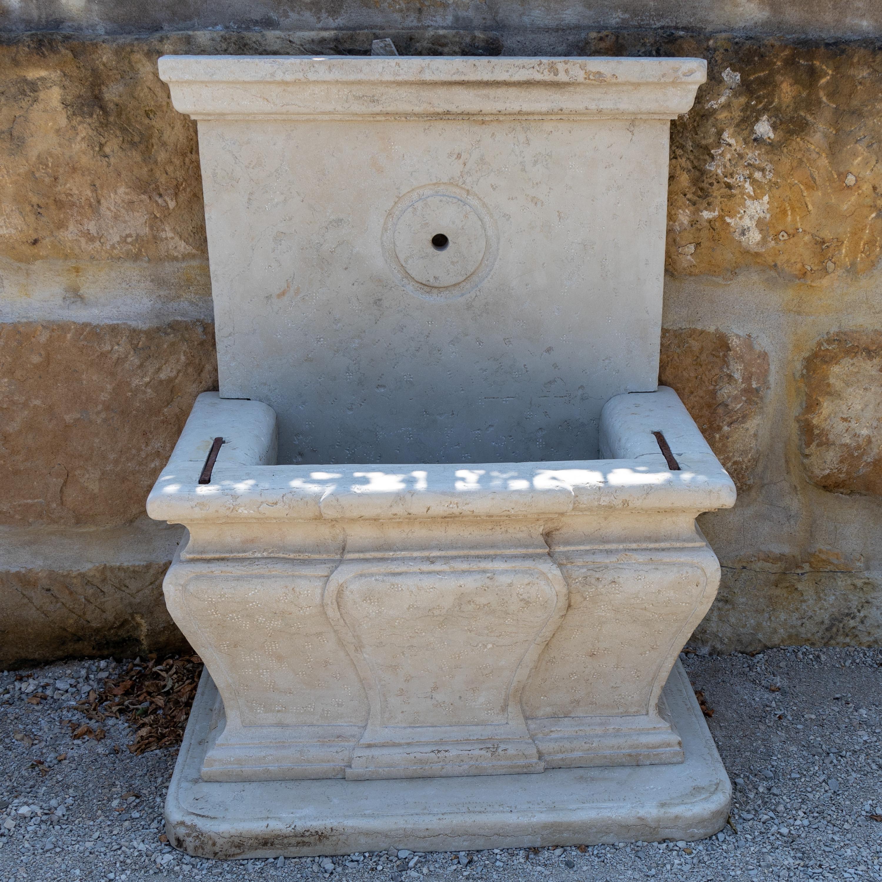Grande fontaine murale en Giallo d'Istria avec bord de bassin profilé et architrave en finition arrière. Hauteur du bord de la cuvette : 72 cm.