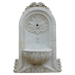 Wall fountain in white Carrara marble, carved with leaf decorations, Italy