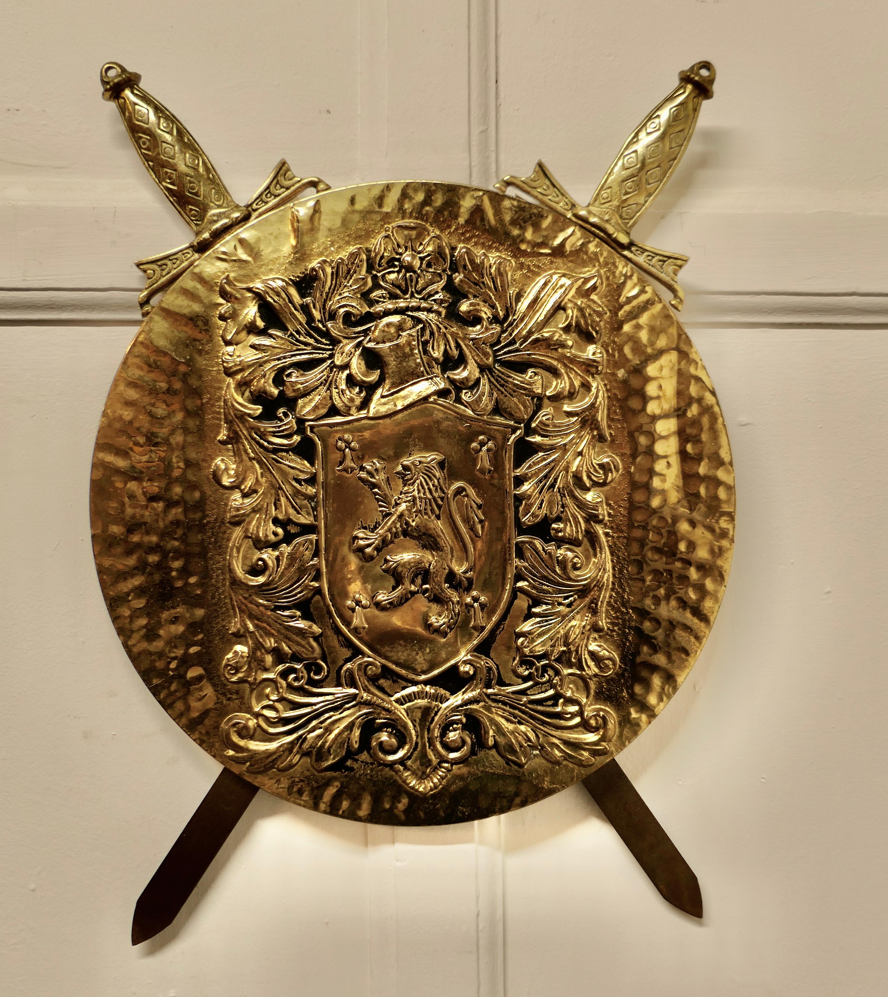 Wall hanging arts and crafts brass shield with cross swords 

A large decorative wall piece the shield is hand beaten and has a Lion Rampant 
The swords are held in the back but not removable, a good looking piece of Traditional Pub