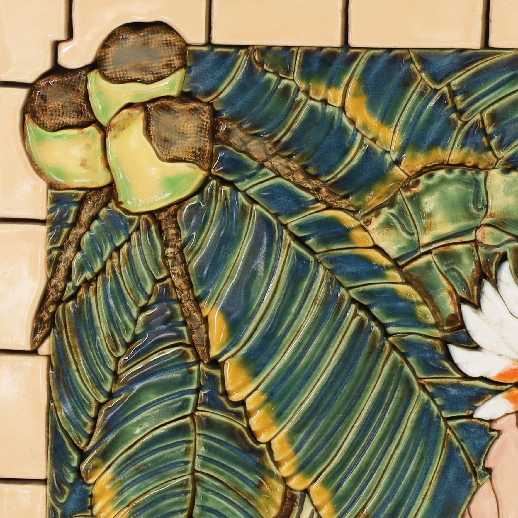 Lofty wall hanging tile art, ambitiously handcrafted in terracotta with each piece cut, fired, decorated, glazed and assembled depicting a cockatoo in a lush jungle setting with birds of paradise. Presented in a faux bamboo frame and labeled on the