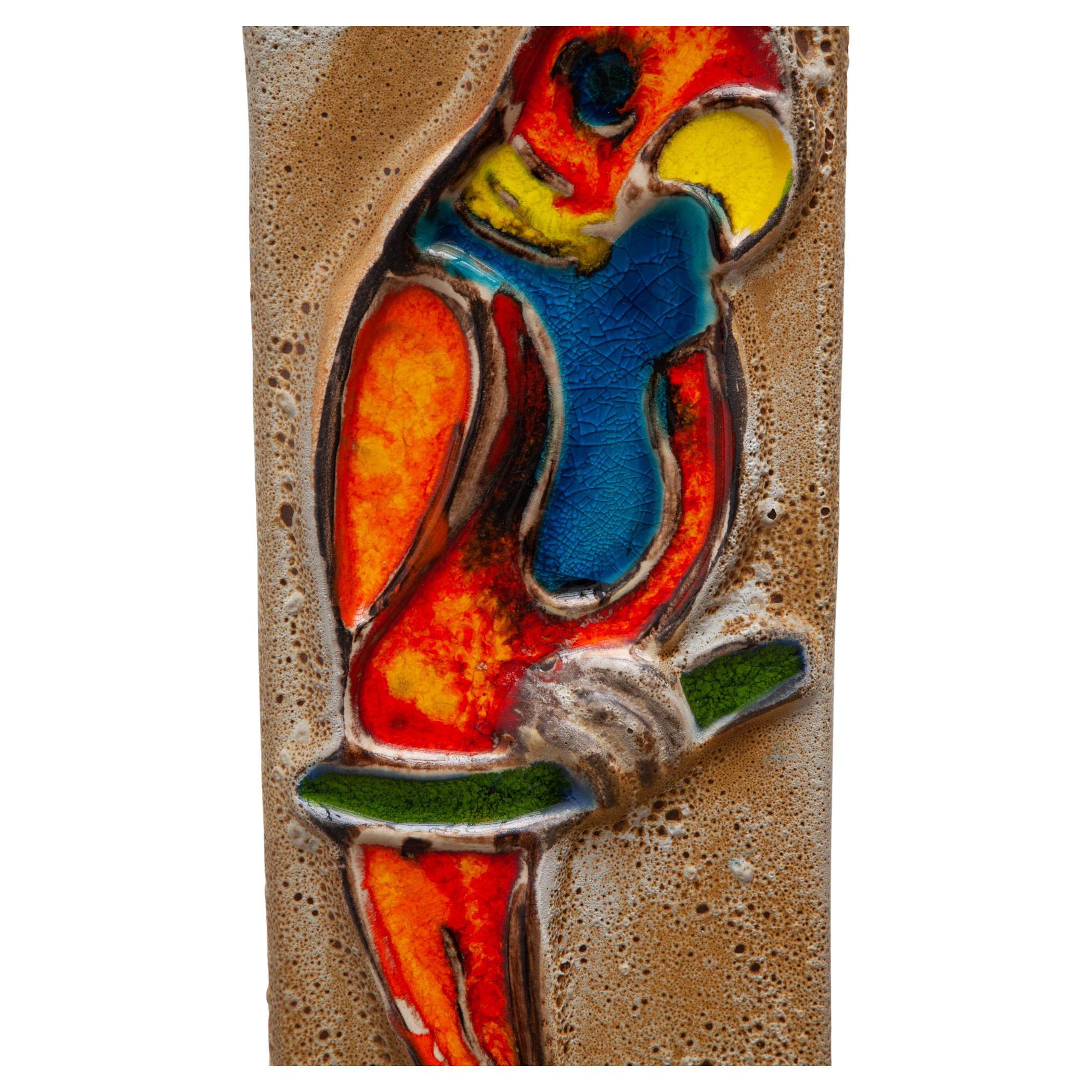 Vintage ceramic glazed wall hanging tile. Relief design of a parrot in colorful glazes and high gloss. Hangs from an iron chain. Dimensions: 20W x 47H x 2D Chain: 28cm.