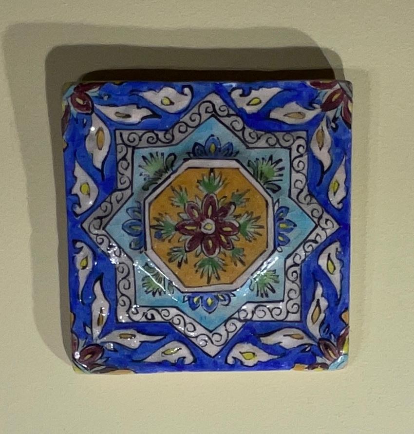 Vintage wall hanging Persian ceramic tile, hand painted and glazed in multicolour floral and geometric motifs.