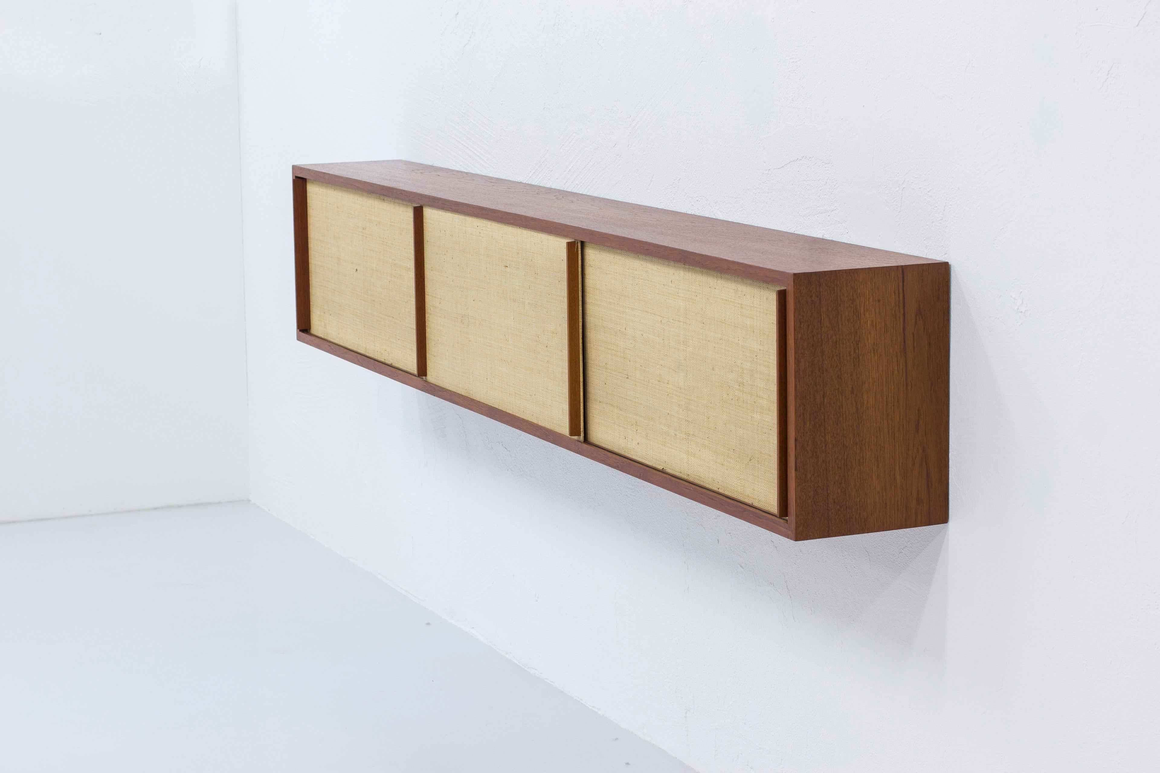 Wall hung sideboard in the style of Illmari Tapiovaara. Produced in Finland during the 1950s. Made from teak with seaweed weave on the doors. The seaweed is very similar in aesthetics as rattan or cane weaved doors as can be seen in pieces by Hans