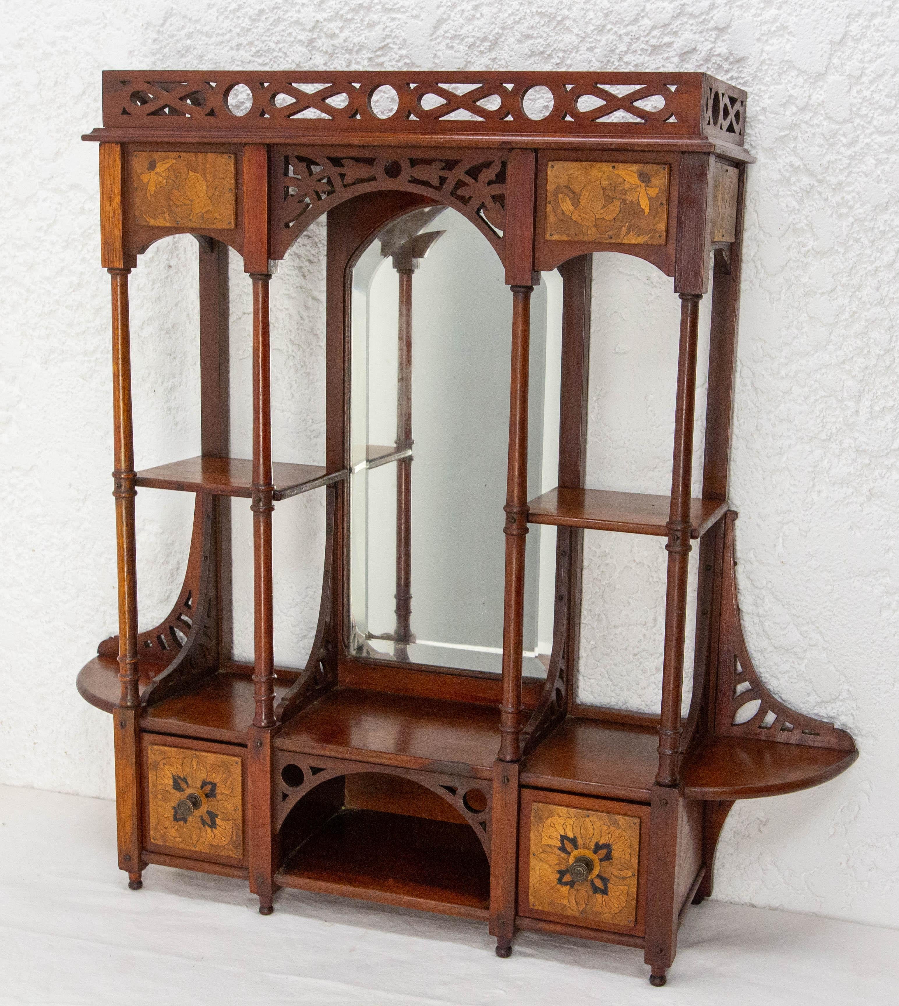Scaffali murali in iroko e legno del periodo Art Nouveau con un  balaustra, colonne, cassetti e nicchia.
Dettagli molto curati: puoi osservare l'elaborata balaustra e l'intarsio ispirato al mondo vegetale tipico dell'Art Nouveau, le sottili colonne