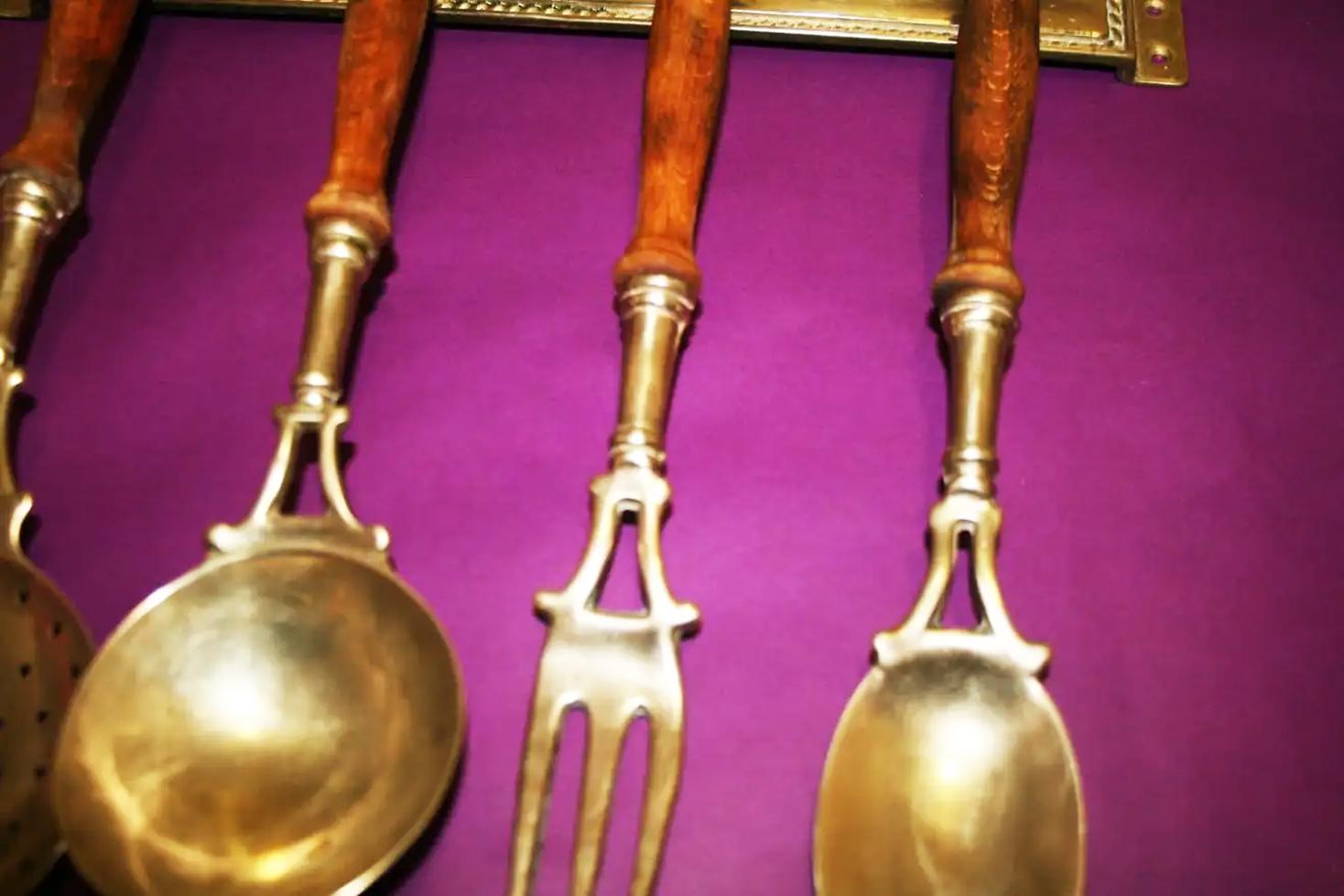 Old kitchen tools or utensils made of wood and brass hanging from a hanging bar. Old kitchen appliance  Midcentury  or Early

Saucepan fork palette and serving pot

This set of brass utensils is ideal to decorate a kitchen of any style, because its