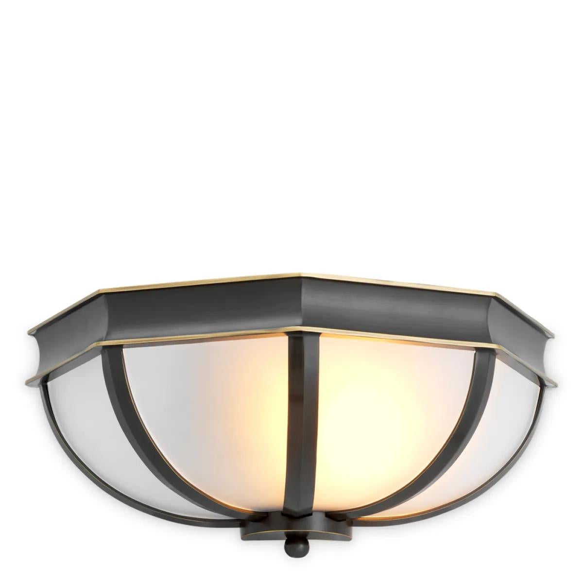 Questa lampada da parete è un apparecchio d'illuminazione elegante e scultoreo che unisce l'eredità al design moderno. Realizzata con una finitura in bronzo e un paralume in vetro bianco, questa lampada da parete conferisce eleganza architettonica e