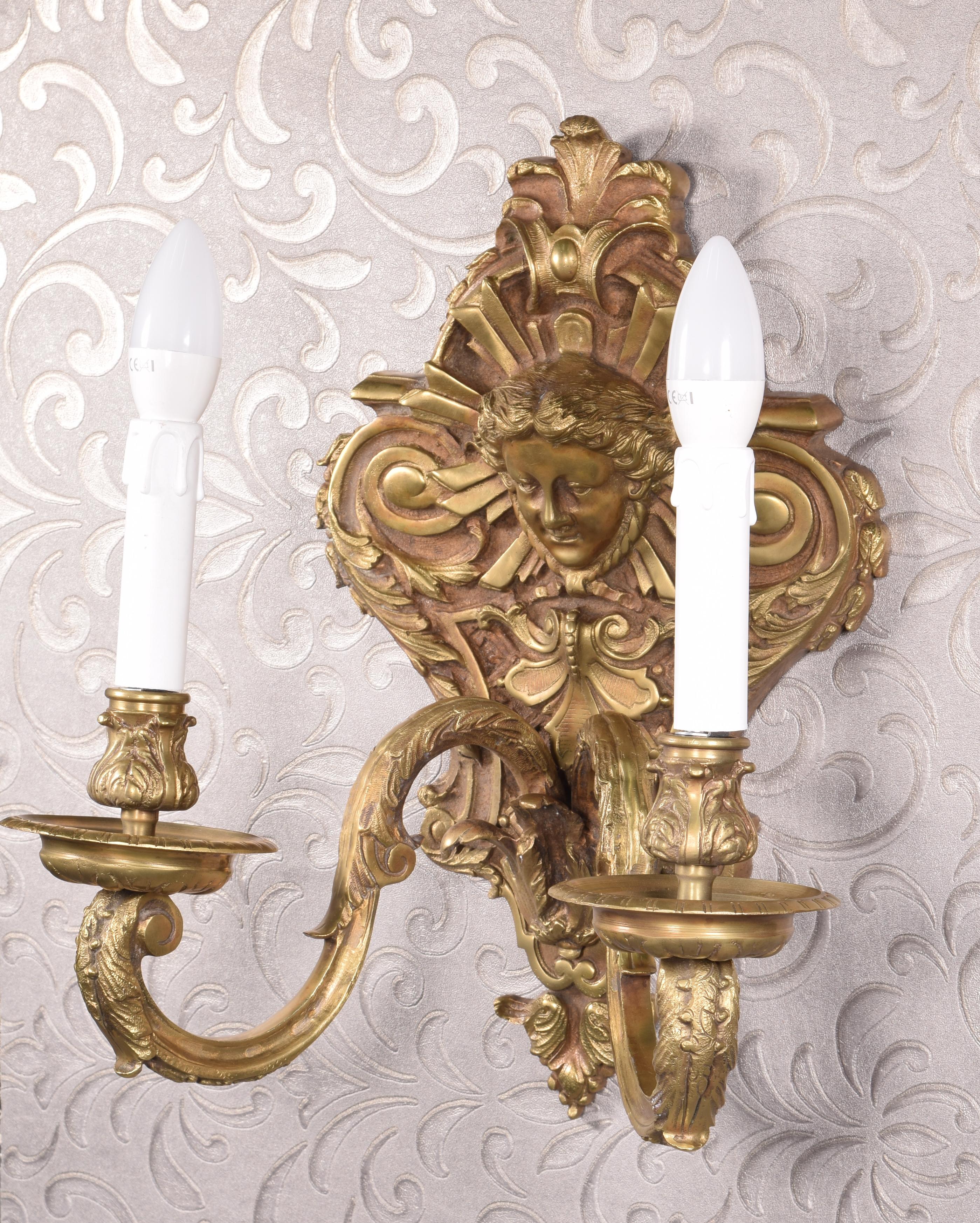 Wall lamp. Bronze.
Wall sconce with two lights  decorated with figurative, vegetal and architectural architectural elements inspired by certain 19th-century Rococo 19th century Rococo souvenirs.
Weight: 13,5 kg
- Measurements: 33x23x40 cms