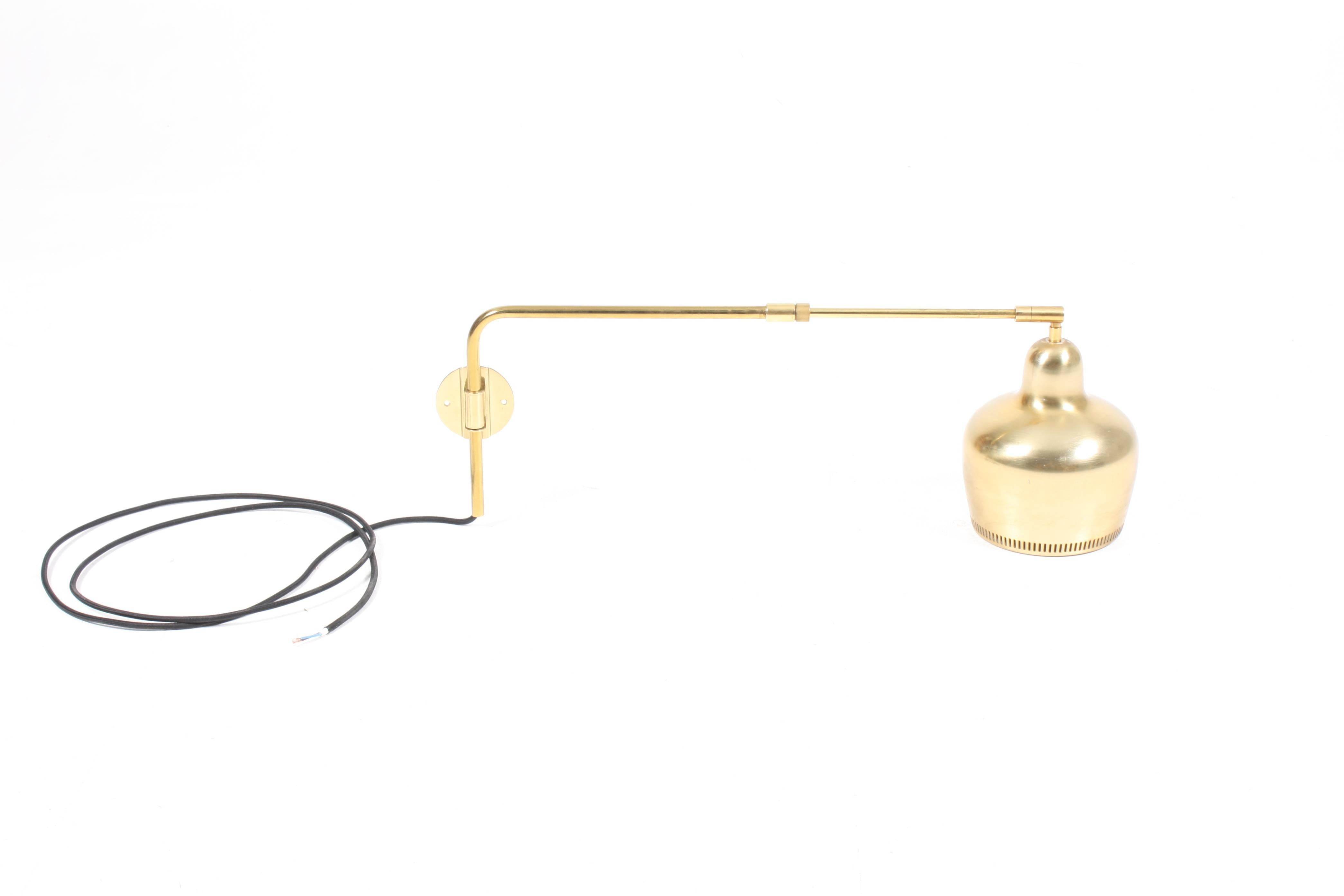 Swivelling wall lamp in patinated brass designed by Finish architect Alvar Aalto for Louis Poulsen Denmark. The lamp is re wired and in good condition. Works well behind a sofa or reading chair.
 