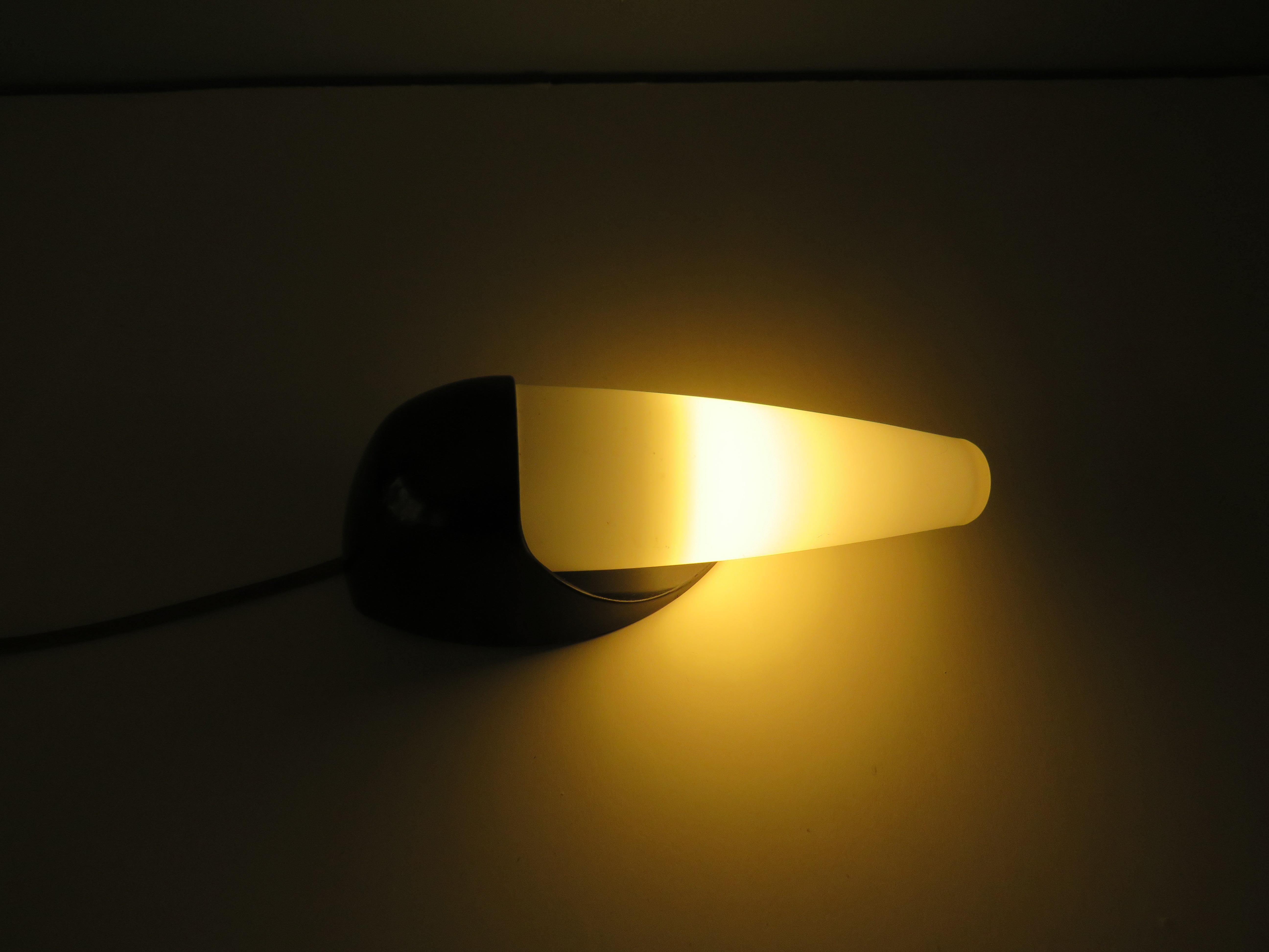 Mid-Century Modern minimalist conical wall lamp made of matt opaline glass and with a black Bakelite frame.
The lamp has a black bakelite E 14 fitting and is in good and working condition. An on and off cord and mechanism is present (unfortunately