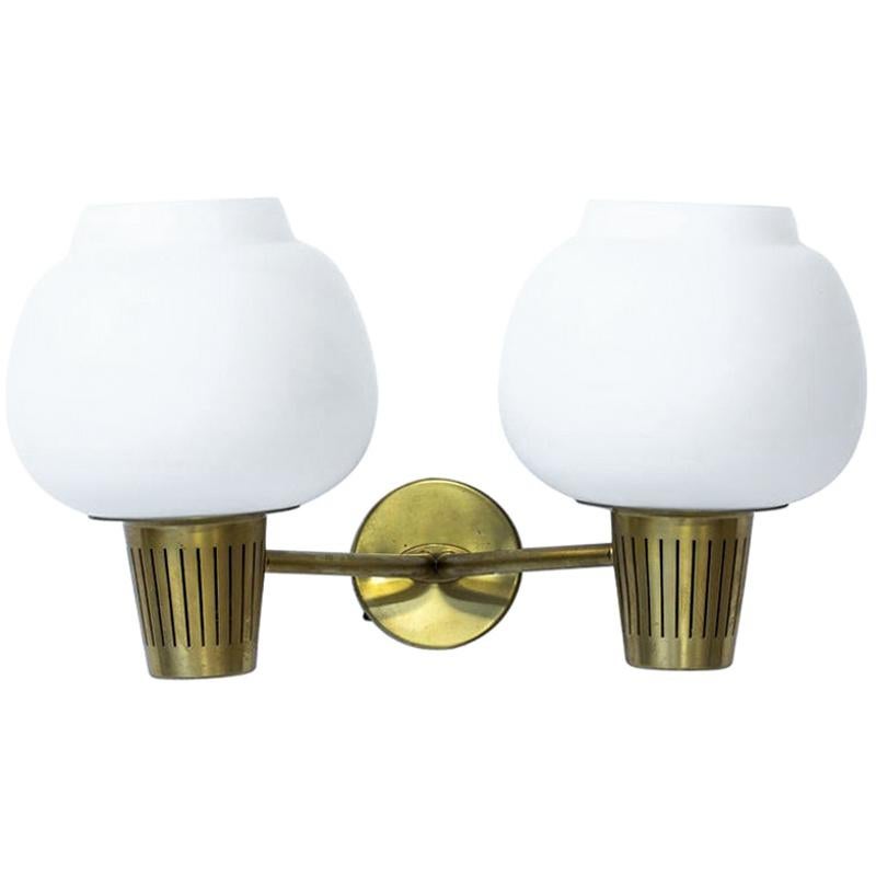 Large two headed wall lamp designed by Hans Bergström for Ateljé Lyktan during the 1950s. Polished brass wall mount with two opaline glass diffusers.