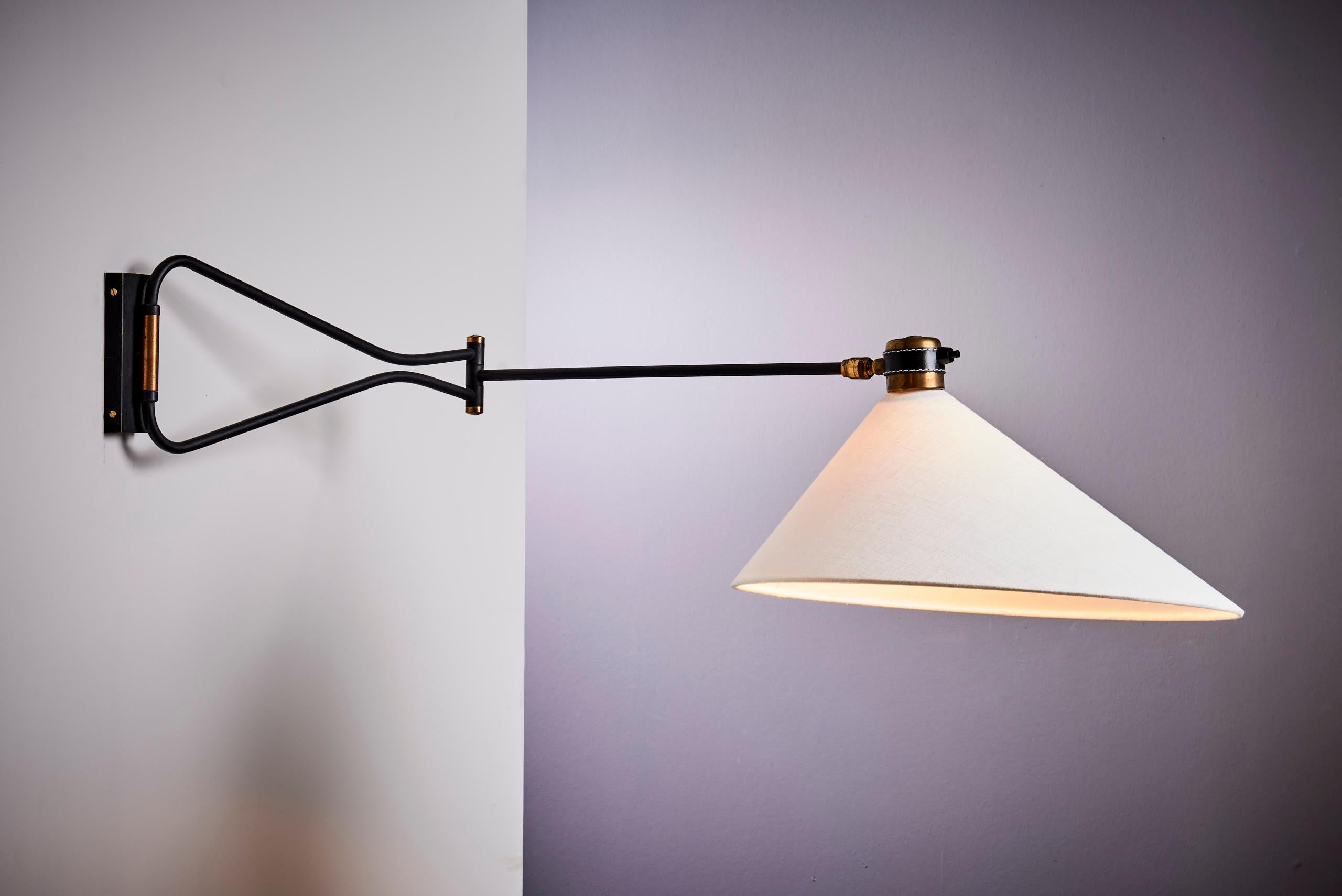 Elegant wall lamp by Maison Arlus, France, dating from circa 1950. This exceptional vintage piece beautifully combines black lacquered metal and brass, capturing the essence of mid-century French design with its timeless sophistication and sleek