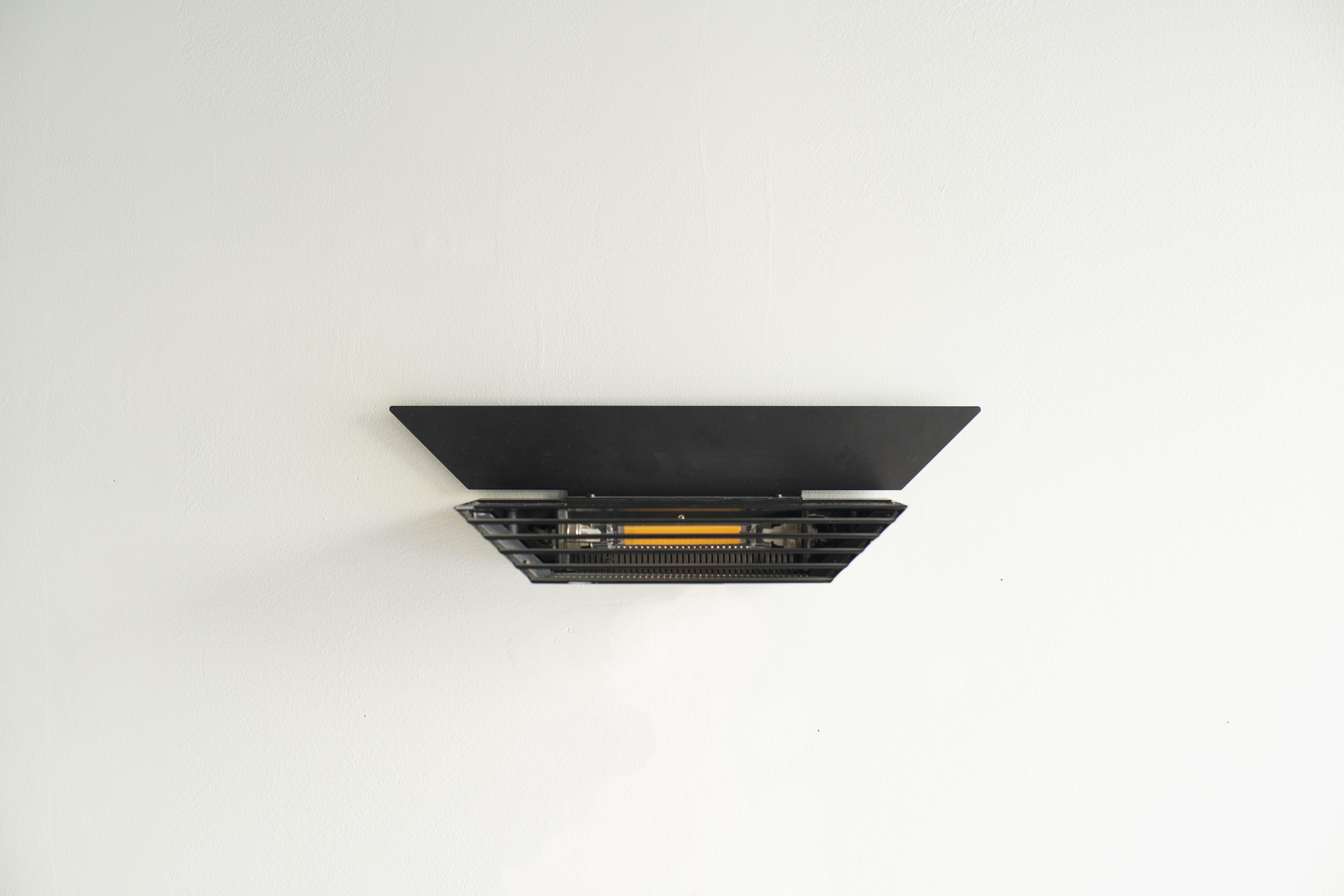 Lámpara de pared diseñada por Raul Barbieri y Giorgio Marianelli para Tronconi. El nombre es Deco Parete. Cuerpo pintado de acero negro. 
El haz de luz va hacia arriba y hacia abajo. Se ajusta al techo.  Pieza escultórica en la pared.

Uso 100-240V.