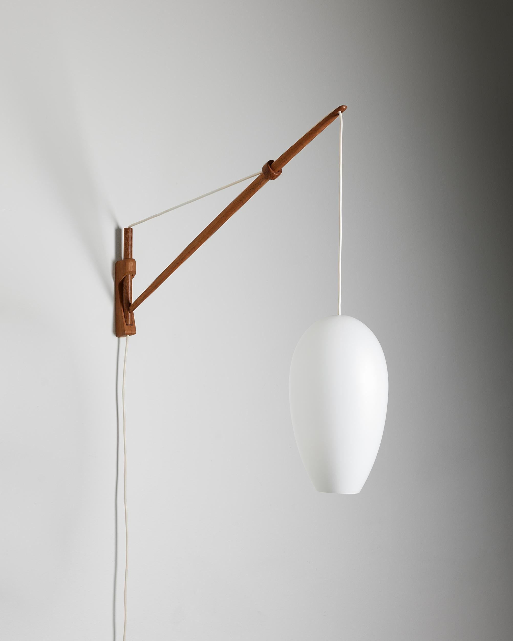 Wall lamp designed by A. Bank Jensen and Kjeld Iversen for Louis Poulsen,
Denmark, 1950s.

Oak and opal glass.

Adjustable drop height.
H: 75 cm
Height of the shade: 32 cm
Diameter of the bottom of the shade: 8 cm
Depth: 79