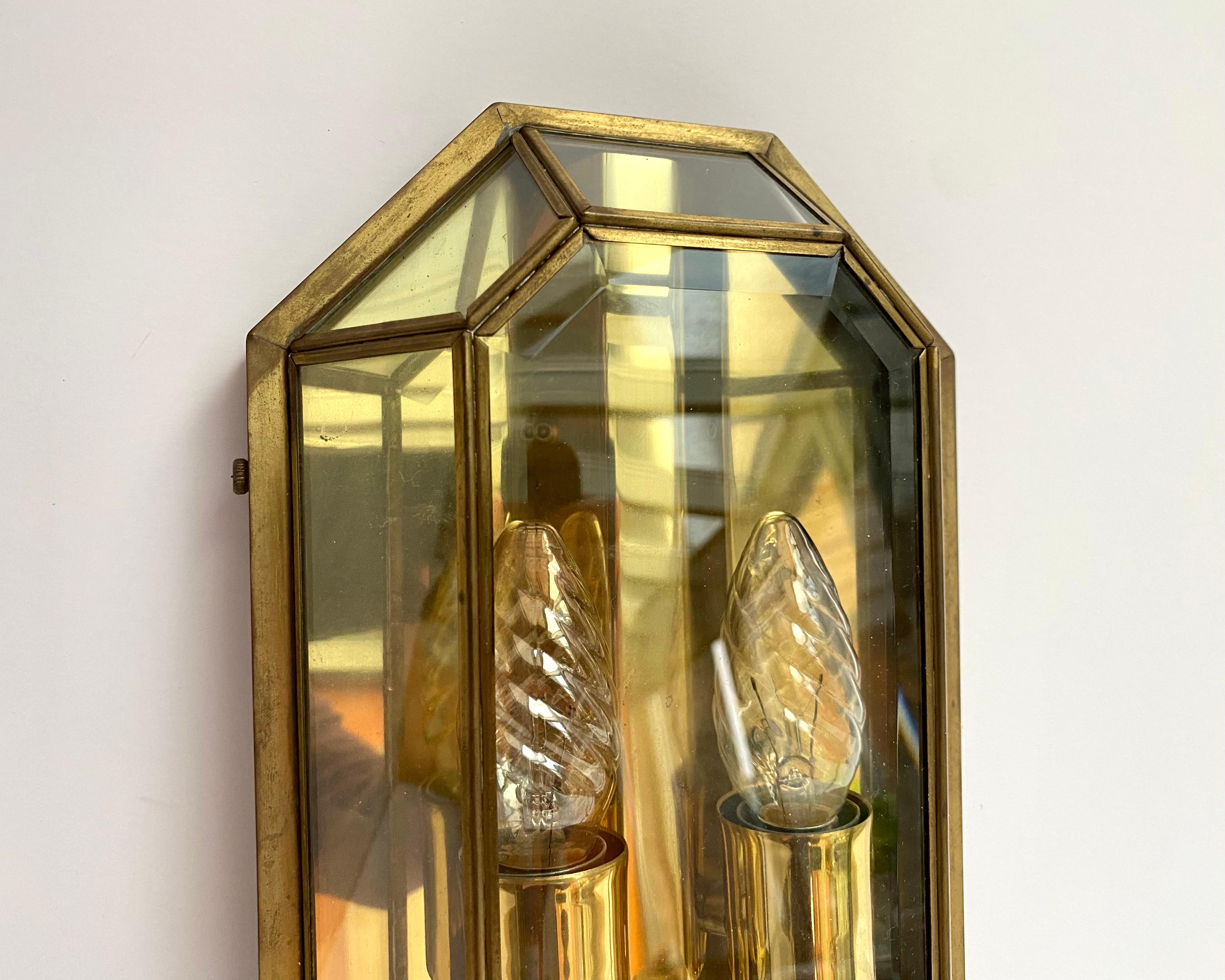 Hollywood regency wall lamp, designed and produced by Lustrerie Deknudt in the 1960's. Handcut glass, clamped in between pleated brass. 

Wall lamps inspired by pure geometric shapes are true symbols of ancient Belgian craft traditions and at the